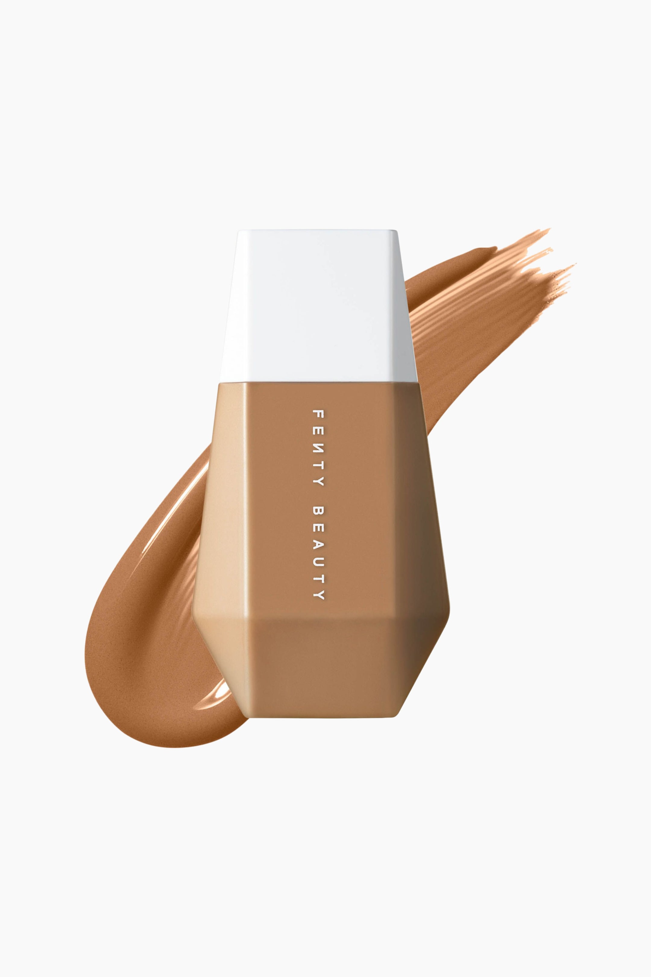 Visa större bild: En flaska Fenty Beauty Eaze Drop Blurring Skin Tint står upprätt och har en geometrisk, mångfacetterad beige kropp med ett platt vitt lock. En diagonal svepning av matchande mediumbrun flytande foundation syns bakom flaskan och löper från nedre vänster till övre höger.