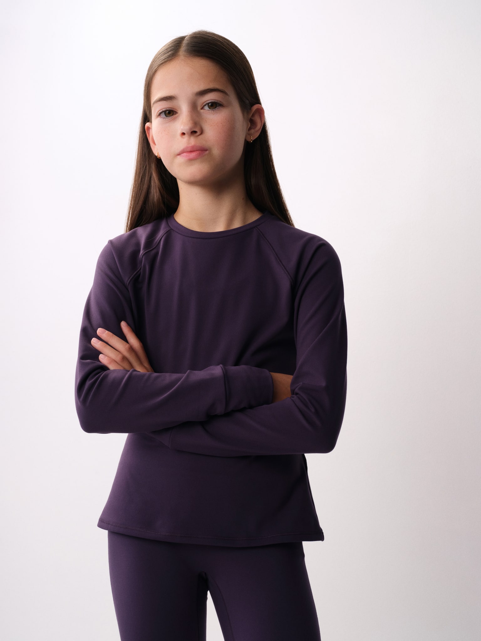 A dark purple long-sleeved top and matching leggings set is shown from the front. The top features a crew neck, raglan sleeves and wide cuffs, while the matching leggings sit close at the waist. - 1
