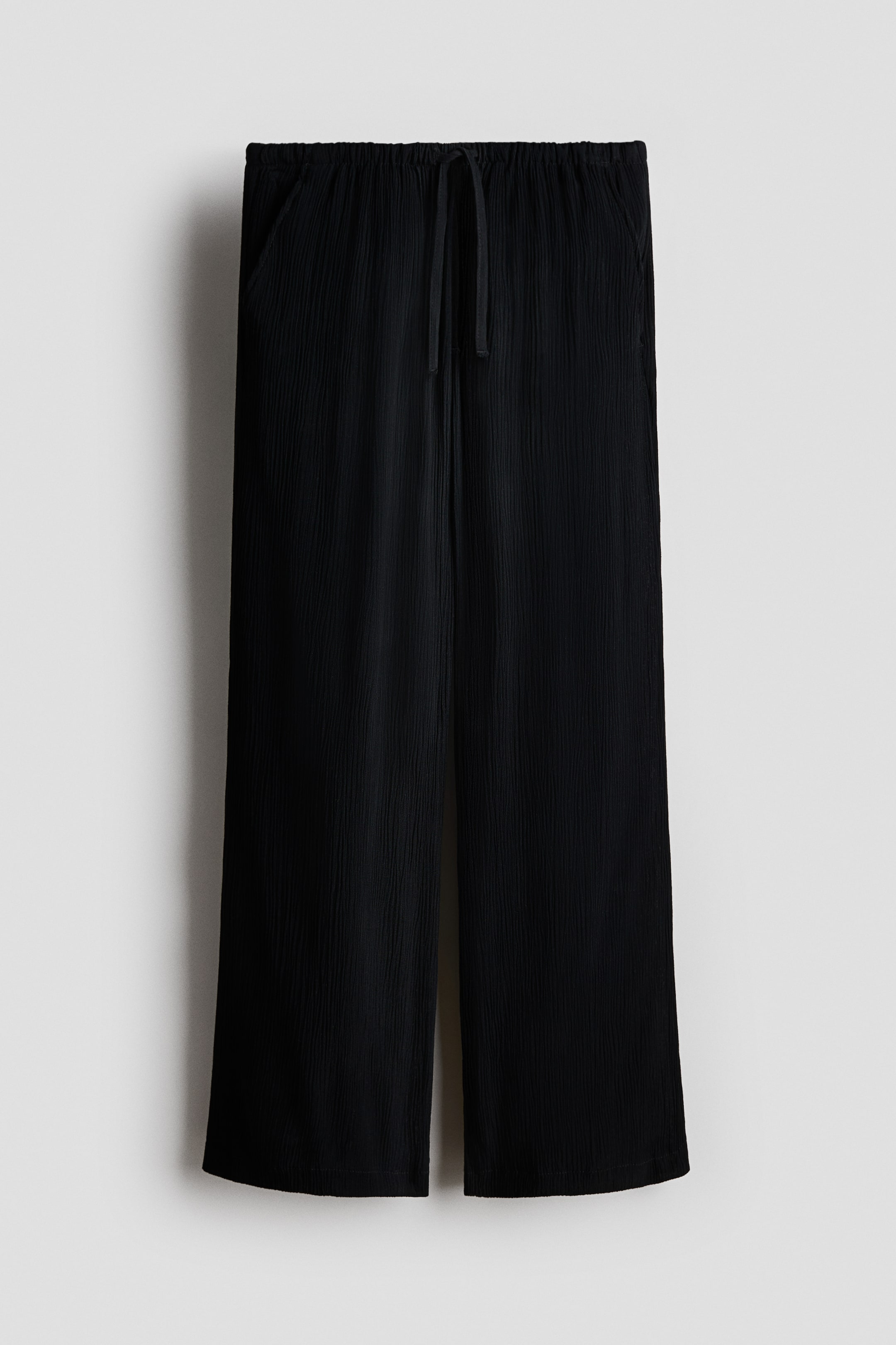 Größeres Bild anzeigen: Schwarze Relaxed‑Fit‑Hose aus Webstoff mit elastischem Bund, gebundenem Kordelzug und schrägen Seitentaschen, Vorderansicht.