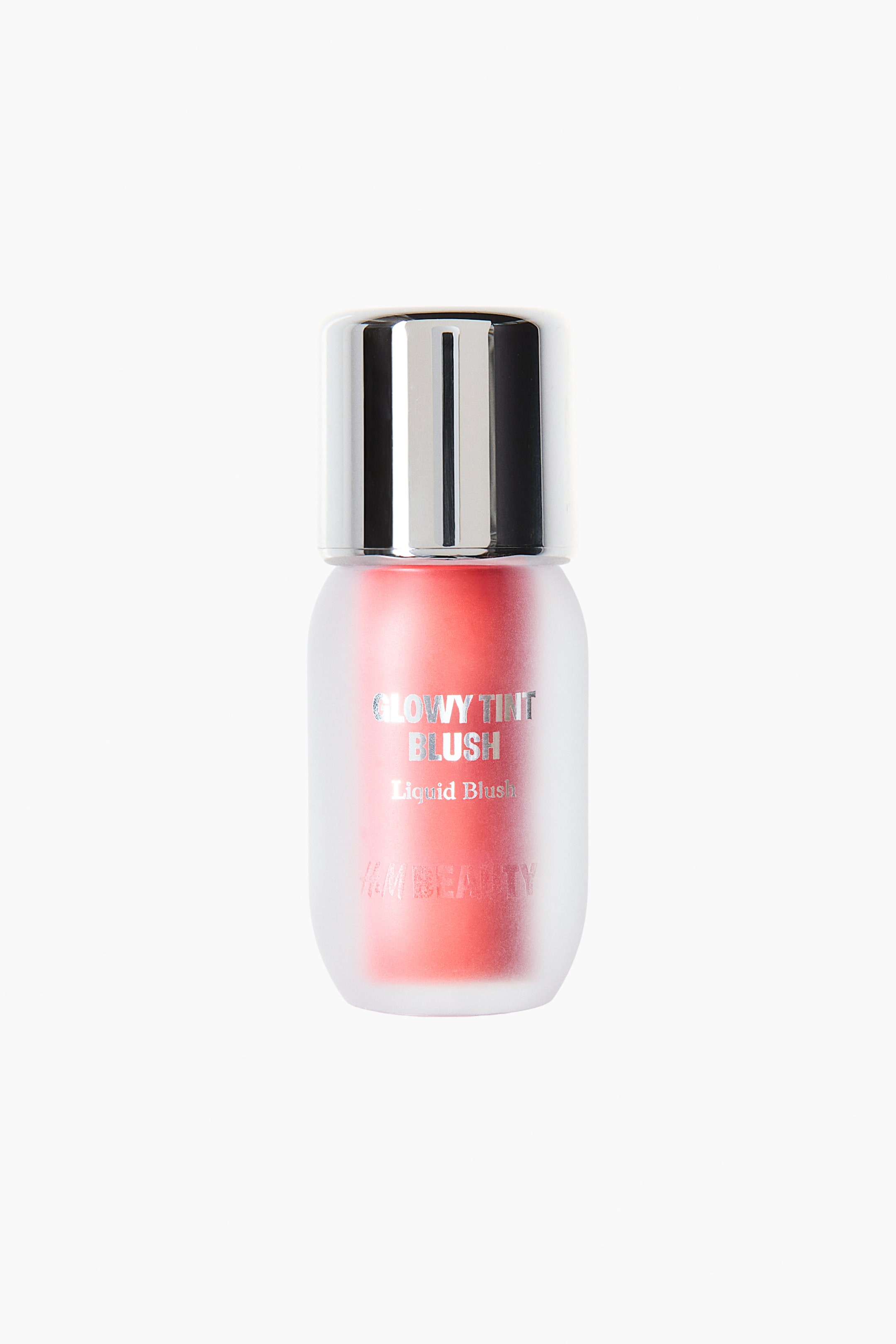 View larger image: A liquid blush bottle is standing upright in a front-facing view, showcasing a frosted, semi-transparent container that reveals a vibrant coral-pink liquid inside. The bottle features a cylindrical, reflective silver cap and silver-toned text on the front reading "GLOWY TINT BLUSH".