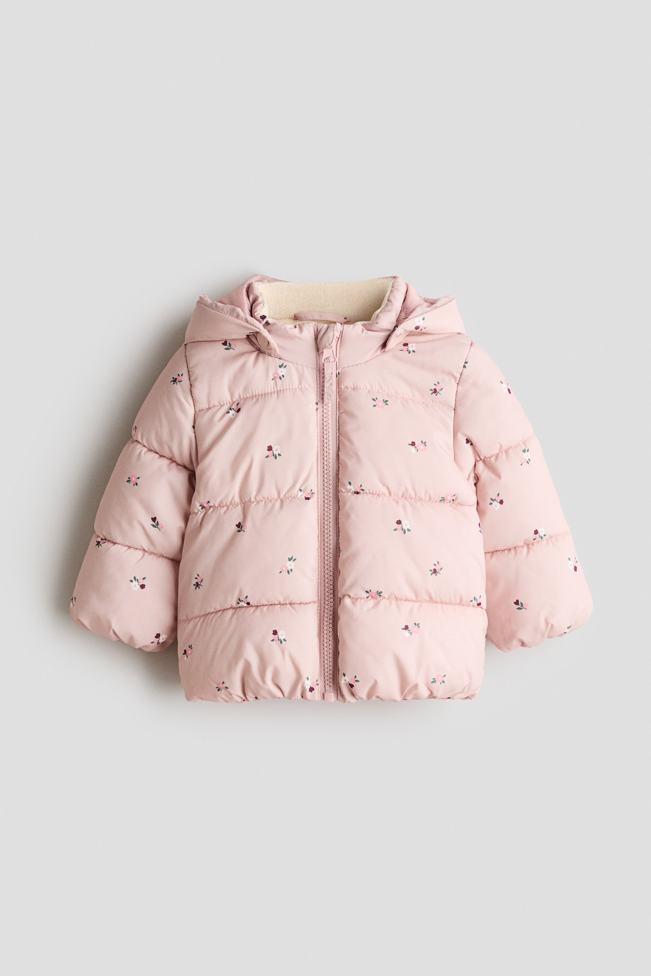 View larger image: A pink padded jacket is shown from the front, featuring an all-over print of small multicolored flowers. It has a full-length front zipper, an attached hood and stand-up collar both lined with cream-colored fleece, and elasticized cuffs and hem.