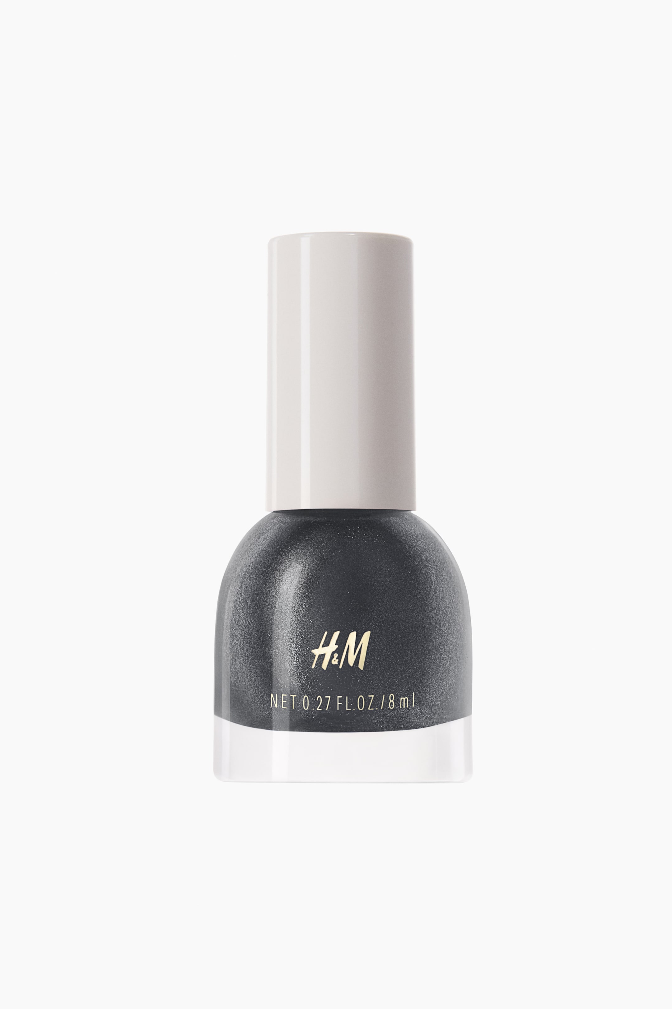 Grotere afbeelding bekijken: Een naar voren gericht nagellakflesje toont een donker houtskoolgrijze, glinsterende lak binnenin zijn afgeronde glazen lichaam, met een heldere basis en een licht beige cilindrische dop. Gouden "H&M" branding en "NET 0.27 FL. OZ. / 8 ml" zijn op de voorkant van het flesje weergegeven.