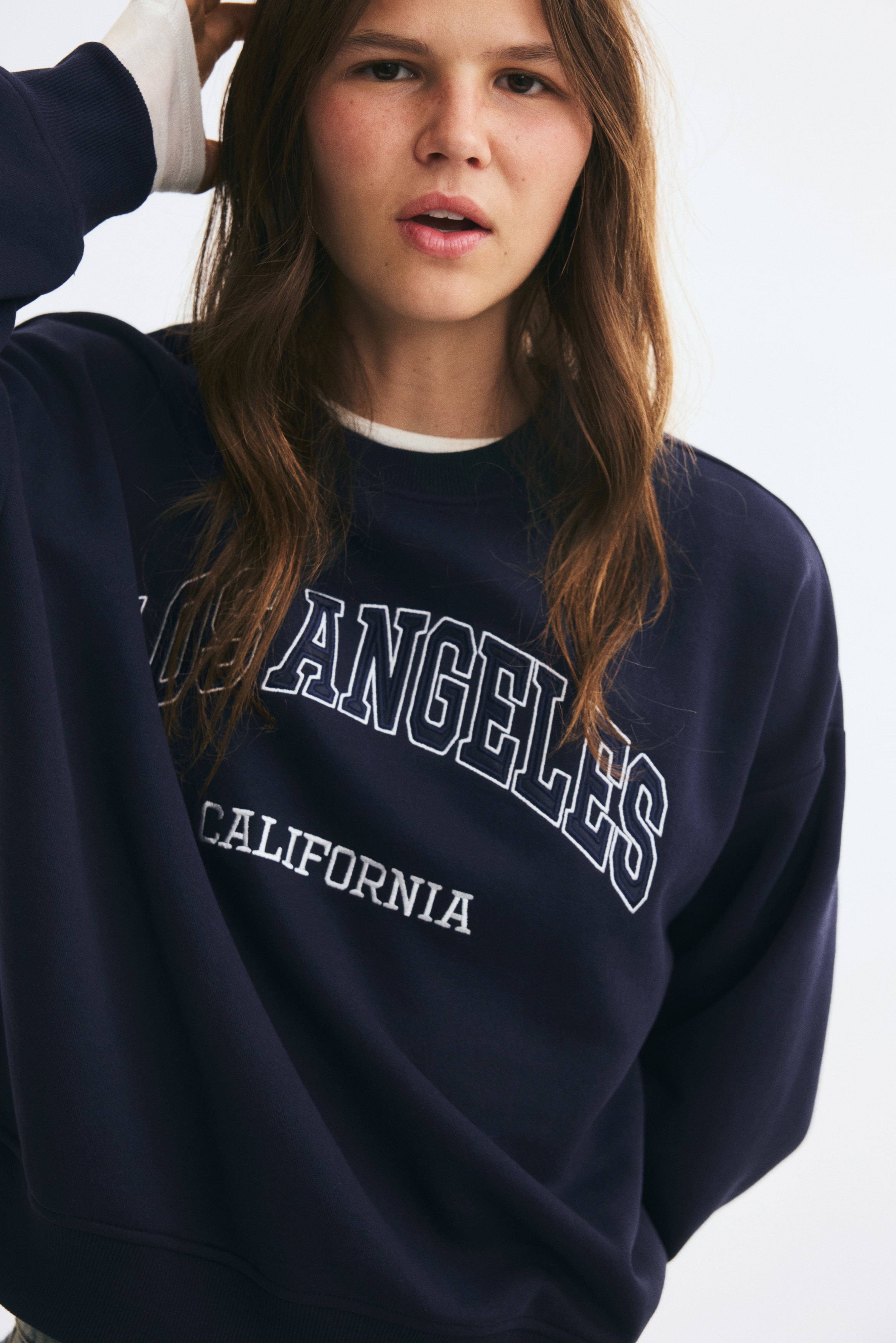 Má»t chiáº¿c Ã¡o sweatshirt oversized mÃ u xanh navy ÄÆ°á»£c chá»¥p tá»« phÃ­a trÆ°á»c, vá»i cá» trÃ²n bo rib, vai trá», bo tay vÃ  gáº¥u Ã¡o bo rib. Pháº§n ngá»±c ÄÆ°á»£c in há»a tiáº¿t phong cÃ¡ch collegiate vá»i dÃ²ng chá»¯ âLOS ANGELESâ uá»n cong vÃ  âCALIFORNIAâ báº±ng chá»¯ in khá»i nhá» hÆ¡n á» phÃ­a dÆ°á»i.