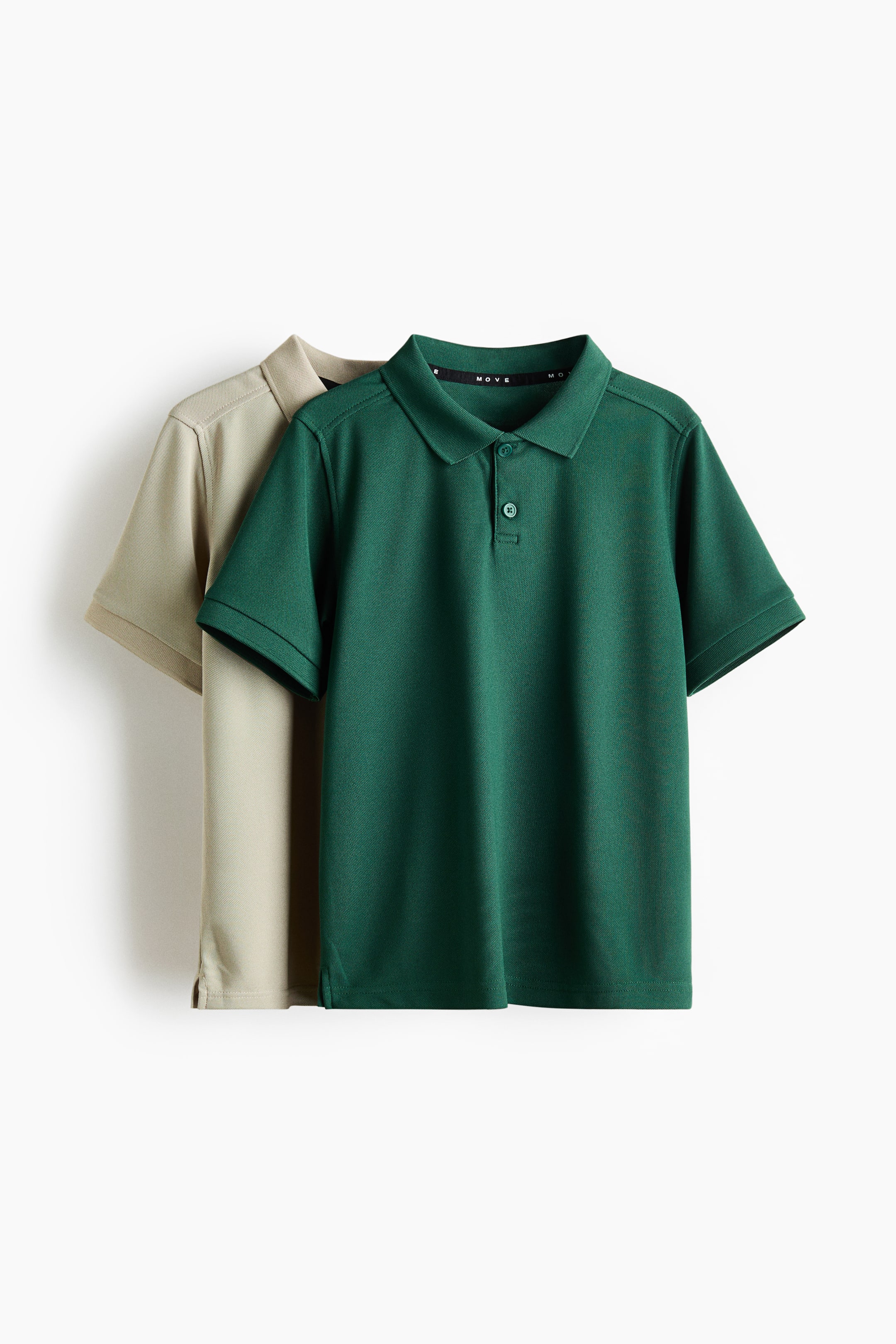 View larger image: A set of two short-sleeved polo shirts is on display, with a dark green shirt positioned at the front and a light beige shirt layered behind. The front green polo shirt features a classic collar, a two-button placket with matching buttons, a subtly textured fabric, and small side vents at the hem.