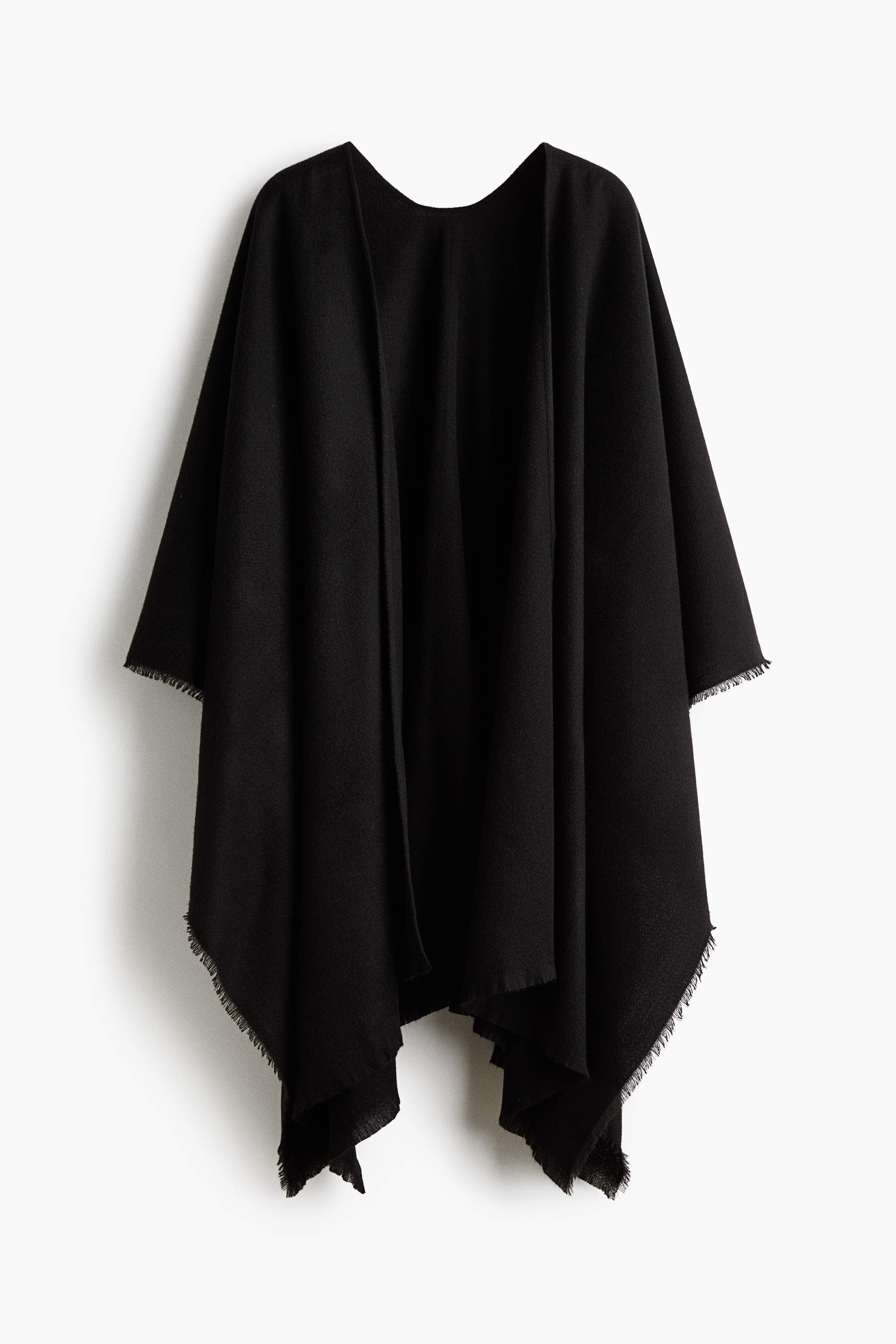 A black fabric wrap with frayed edges is worn by the model, draped over their shoulders and crossed arms. The wrap is styled with high-waisted black trousers and oversized black shield sunglasses.