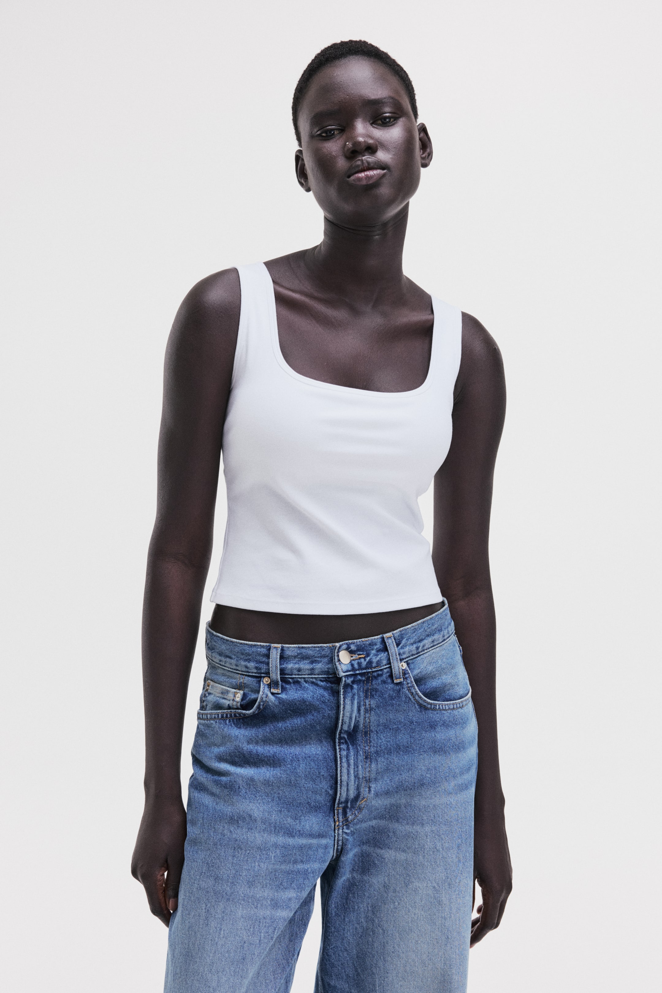 View larger image: A white tank top featuring a square neckline, wide shoulder straps and a fitted, cropped length, shown from the front.