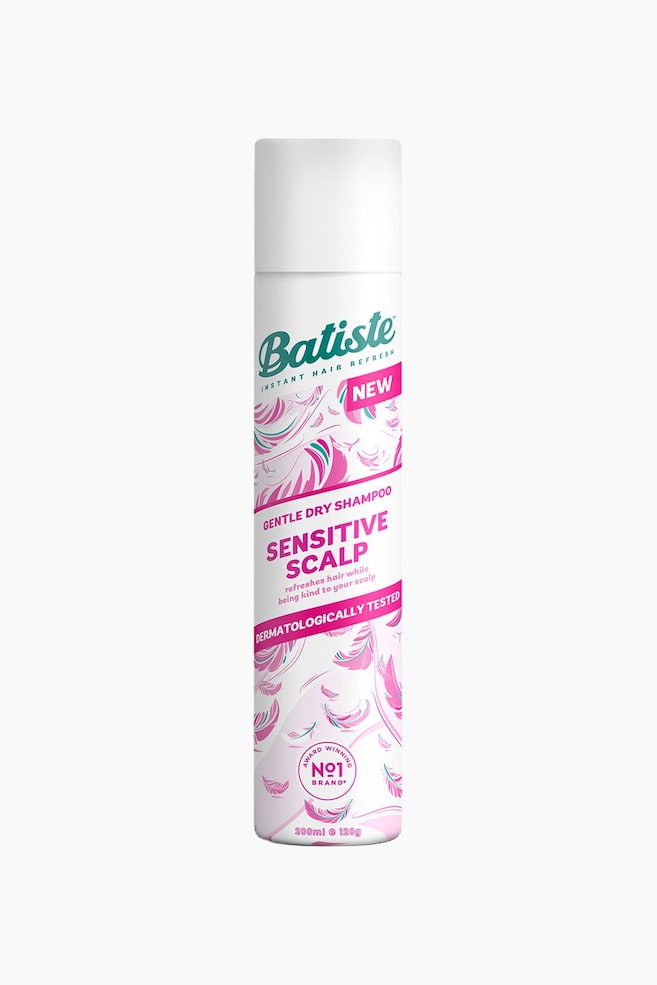 En hvid, cylindrisk aerosoldåse af Batiste Instant Hair Refresh Gentle Dry Shampoo Sensitive Scalp står oprejst og vender fremad. Dens etiket viser mærkenavnet i teal, bannere med 'NEW' og 'DERMATOLOGICALLY TESTED' i pink samt fjerlignende mønstre i pink og teal. - 1