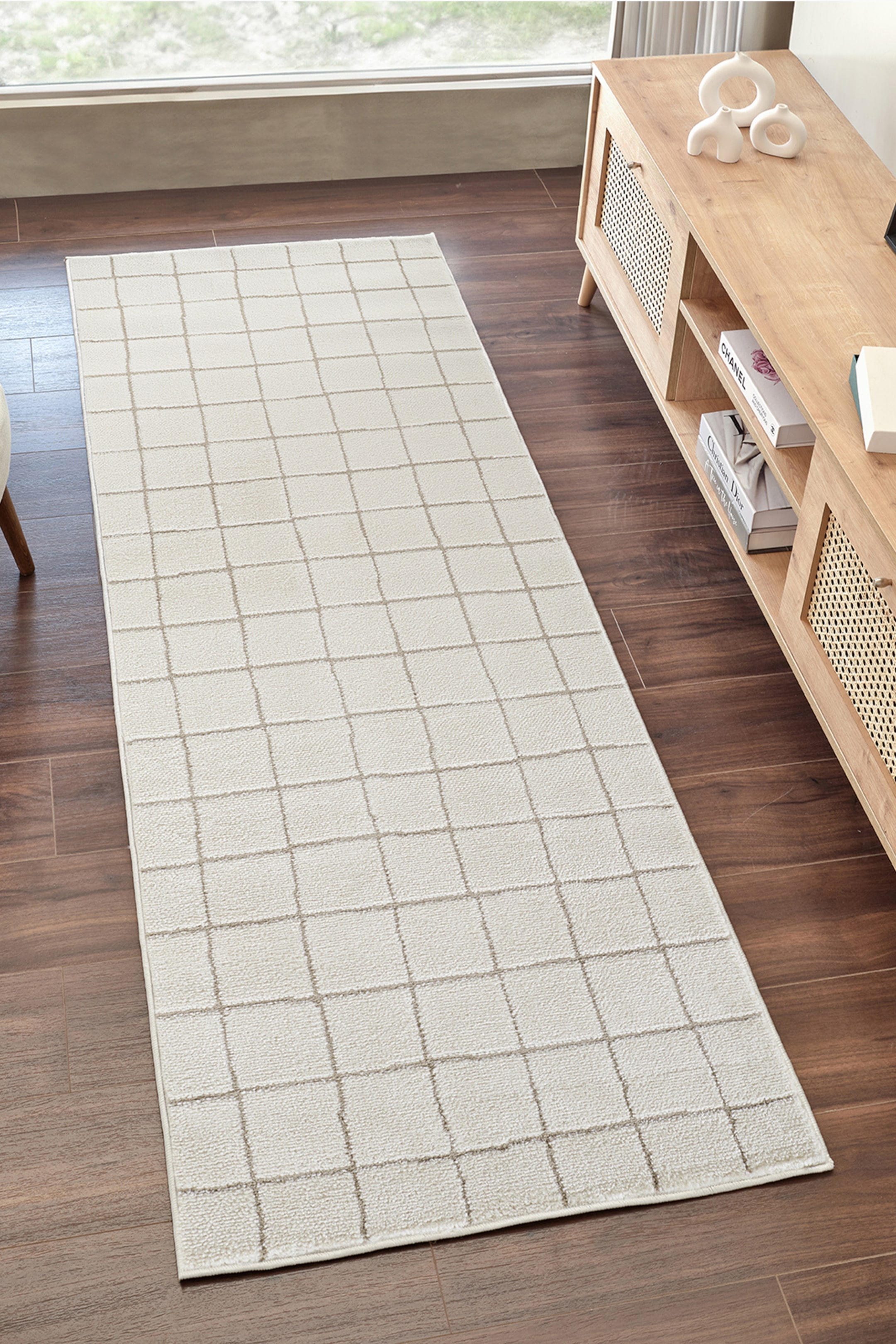 View larger image: The runner rug features a light beige base with a taupe grid pattern, showcasing a low-pile, textured surface. It extends lengthwise, presenting its full design from an overhead view.