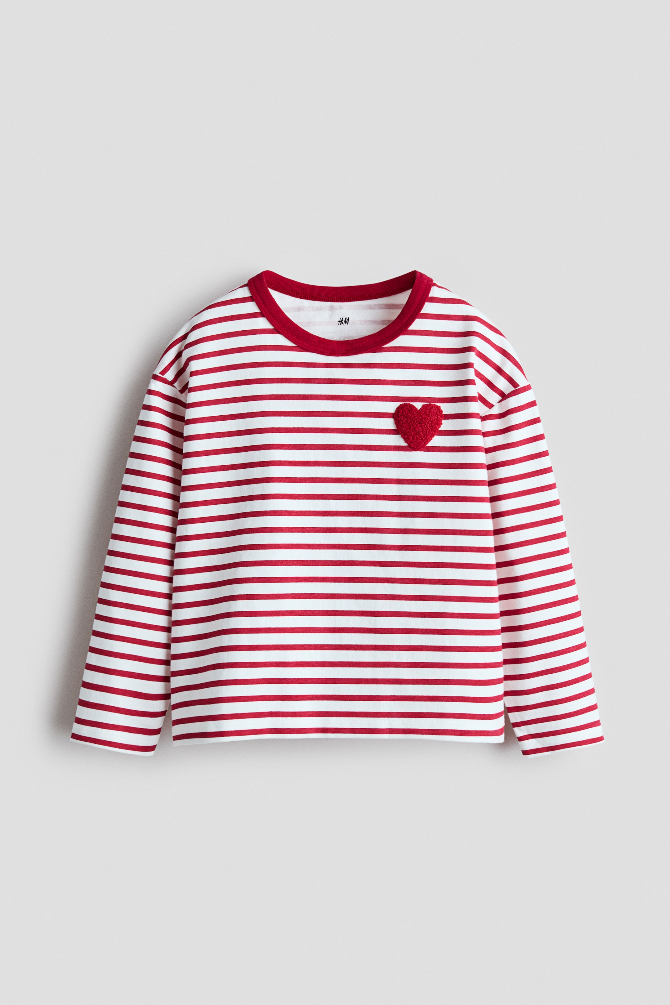 View larger image: This long-sleeve top showcases a red and white horizontal stripe pattern, complete with a red ribbed round neck and a red textured heart appliqué on the left chest.