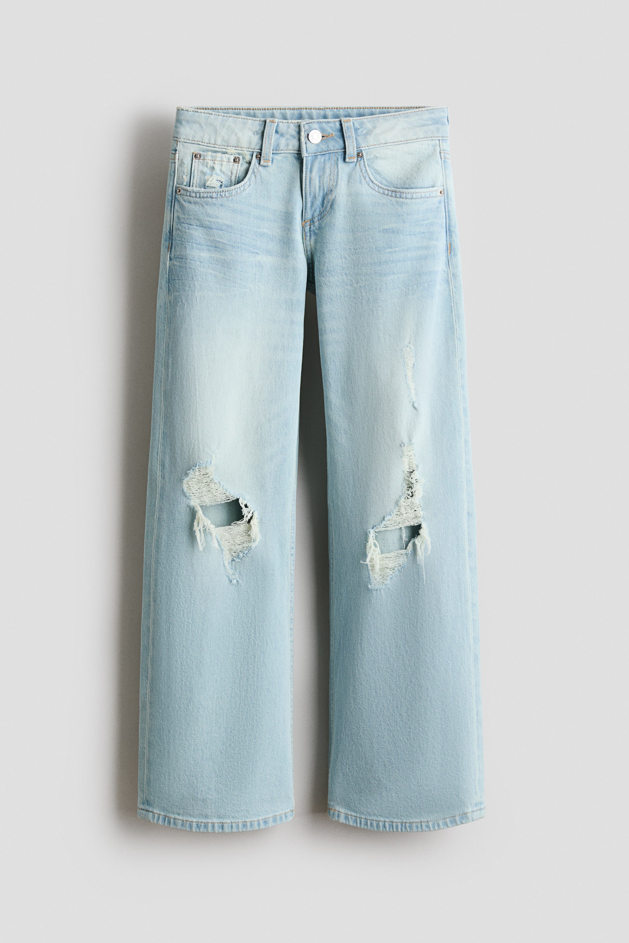 Se større billede: Et par lyseblå, 5-lomme bomuldsdenim jeans præsenteres forfra. De har lav talje, lynlås med knap og brede ben, samt slidte detaljer inklusive huller på begge knæ.