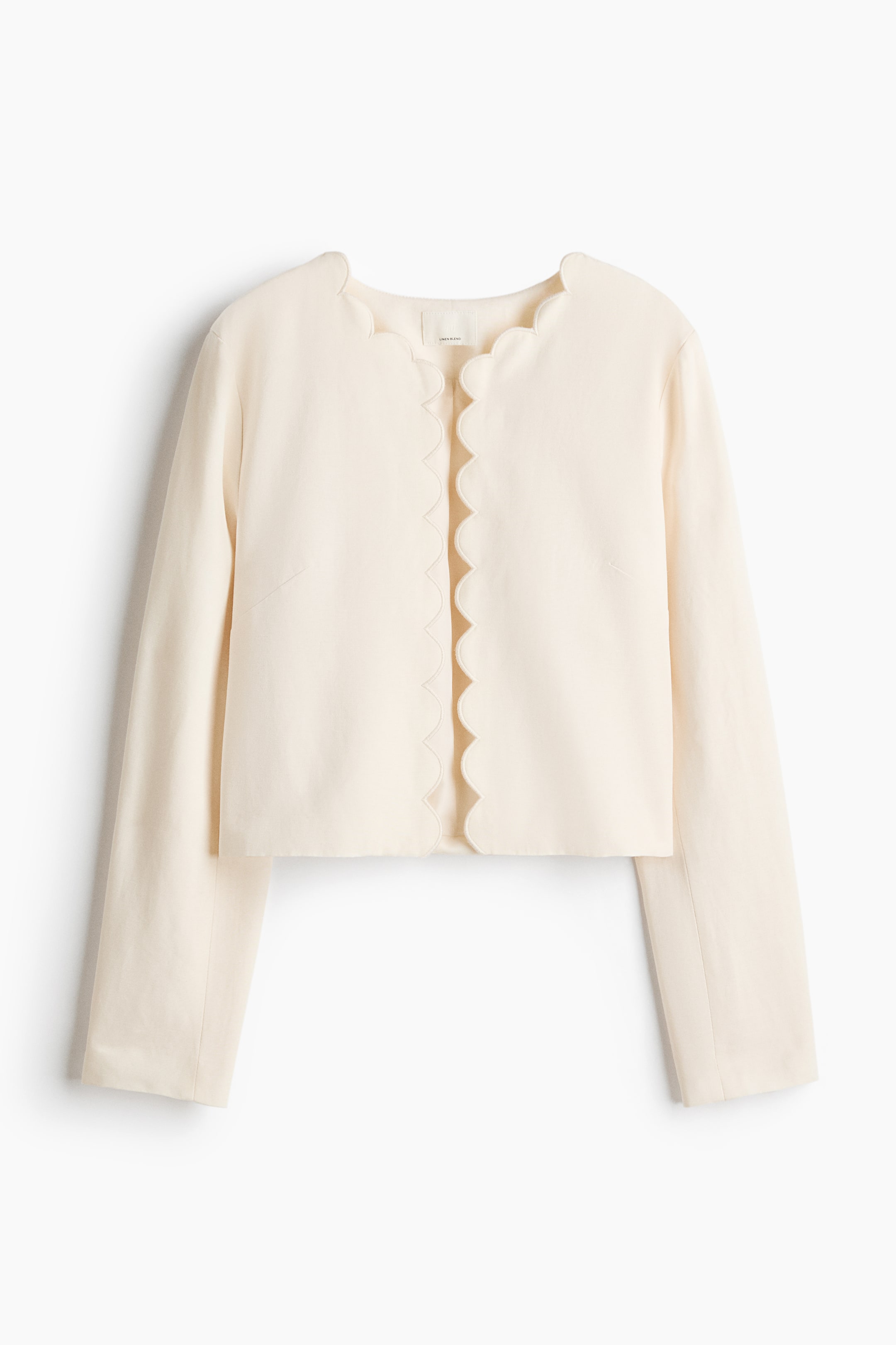View larger image: The light-coloured woven jacket is showcasing a front view, featuring a round neckline and an open front, both detailed with scalloped edges.