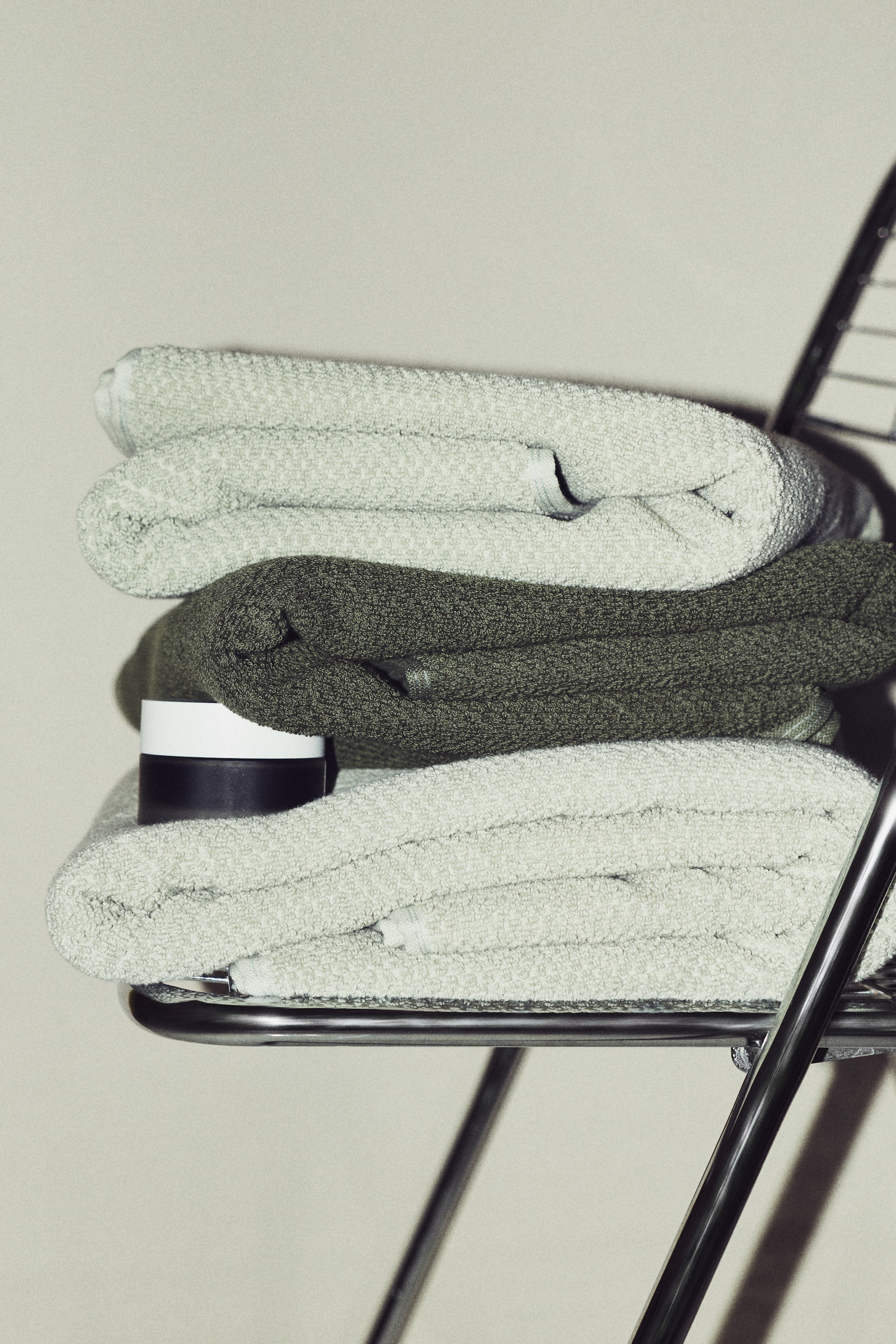 View larger image: Three cotton terry bath towels are neatly folded and stacked, showcasing light green towels at the top and bottom, with a darker green towel placed in between.