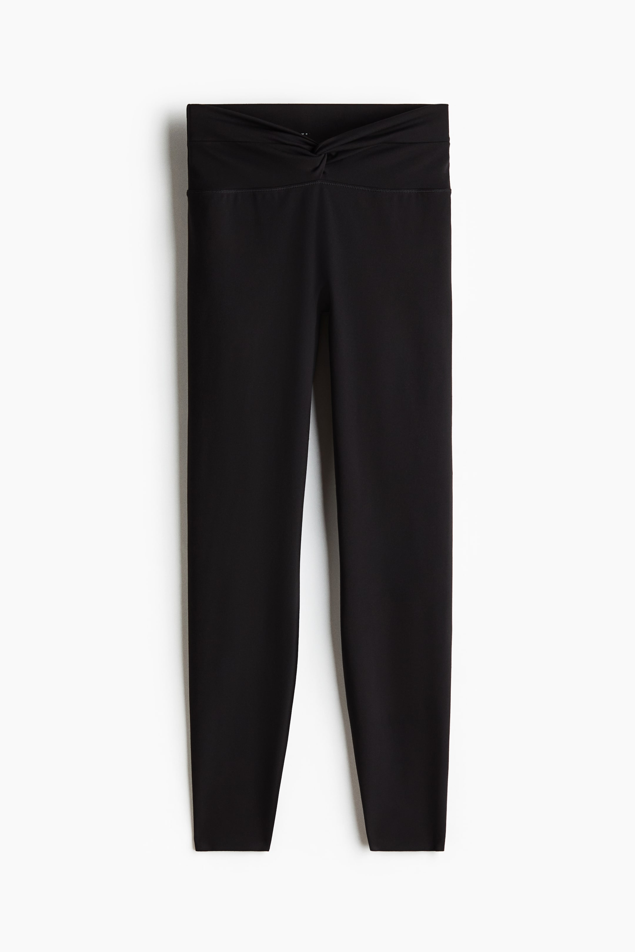 Xem ảnh lớn hơn: Quần legging màu đen được chụp ở góc nhìn phía trước, thể hiện phần cạp rộng, cao với chi tiết xoắn nổi bật ở giữa.