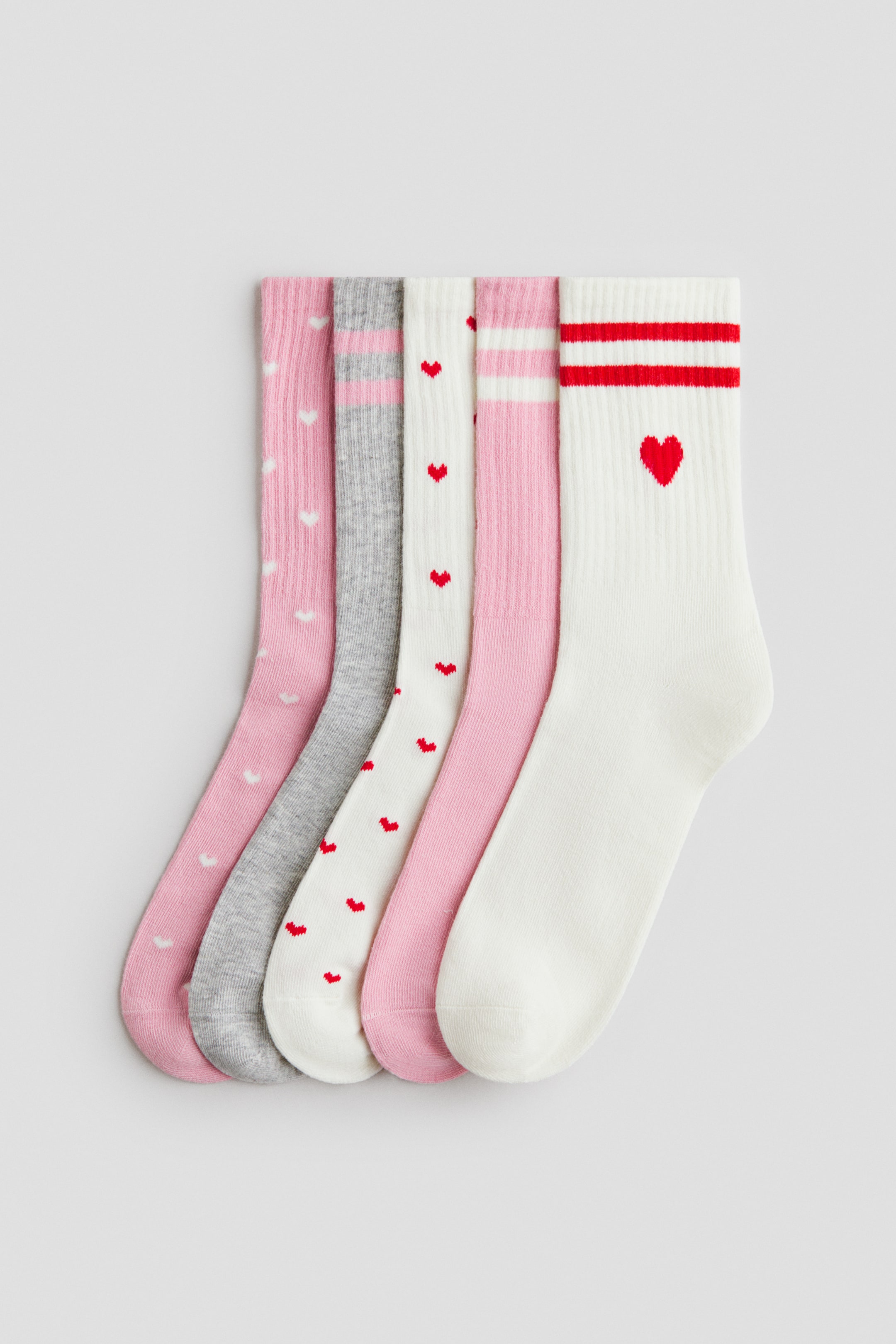 Visualizza l'immagine ingrandita: Calzini in maglia fine in morbido misto cotone, con gambali a coste e bordi elasticizzati, posati in piano e rivolti verso il davanti. Il set di cinque calzini include varianti nei colori rosa, grigio e bianco, con design a cuori bianchi, cuori rossi sparsi e fantasie a righe in rosa o rosso.