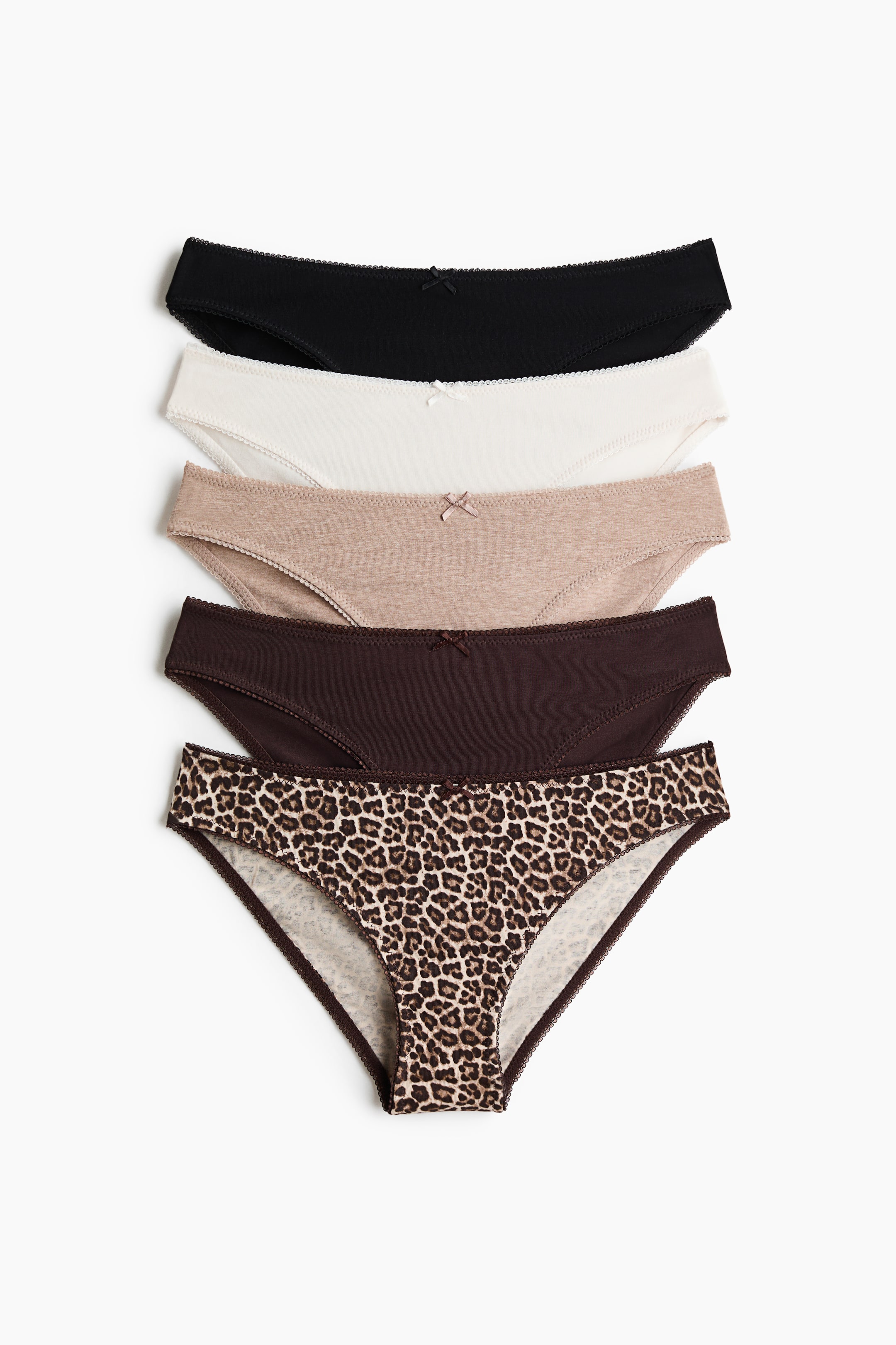 View larger image: Five women's briefs are shown in a stacked front view, each featuring a small bow at the center front waistband and scalloped trim along the edges. The briefs come in solid black, cream, light beige, dark brown, and a leopard print.