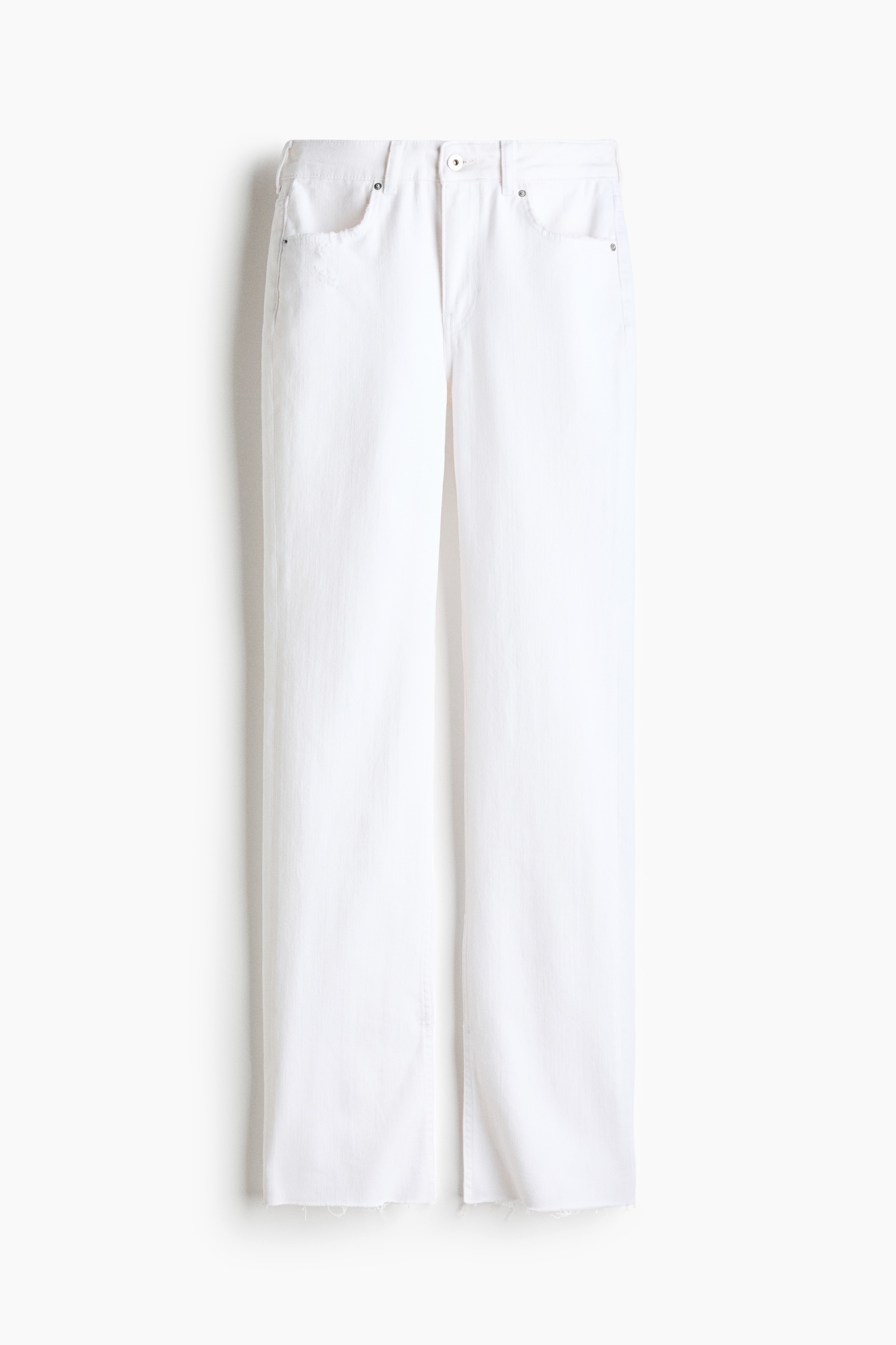 Jeans in denim bianco dalla vestibilità slim, con uno spacco sullâorlo posteriore, indossati dalla modella. La modella è in posa di profilo laterale e abbina i jeans a un top smanicato color crema e sandali aperti in punta.