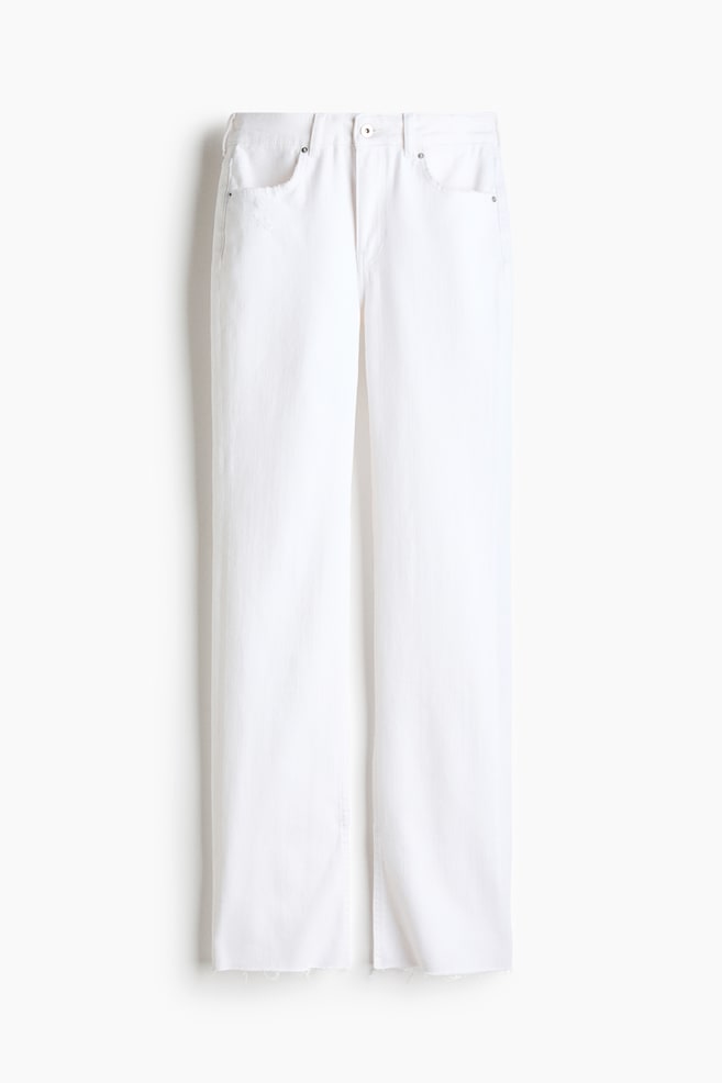 Forfra af hvide five-pocket-denimjeans med almindelig talje, knaplukning og lynlÃ¥sgylp. Jeansene har en straight-leg-silhuet med rÃ¥, let flossede buksekanter. - 1