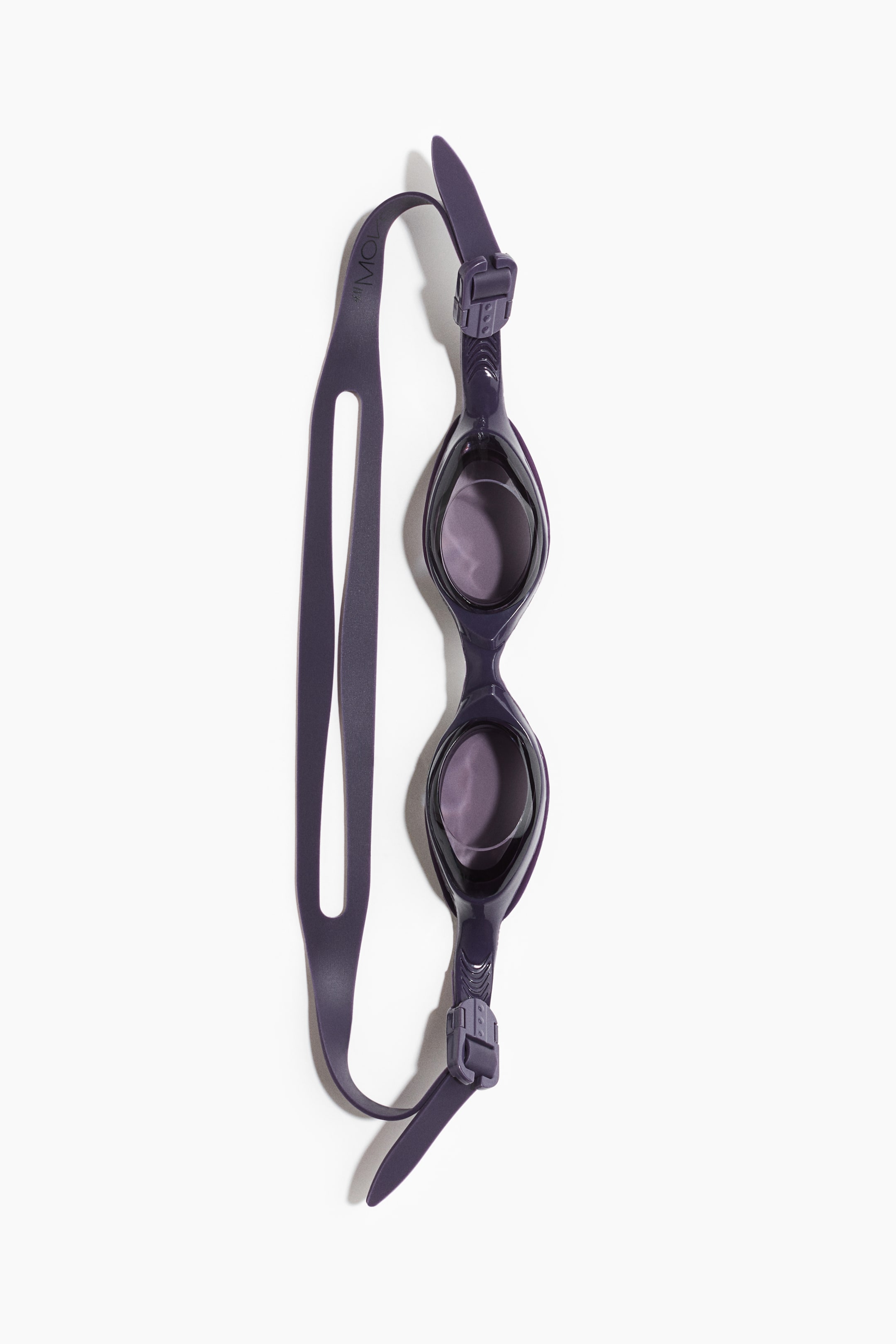 View larger image: Swimming goggles are displayed lying flat and angled diagonally, featuring tinted polycarbonate lenses set within dark purple frames. An adjustable, split dark purple silicone strap connects to the frames with matching buckles.