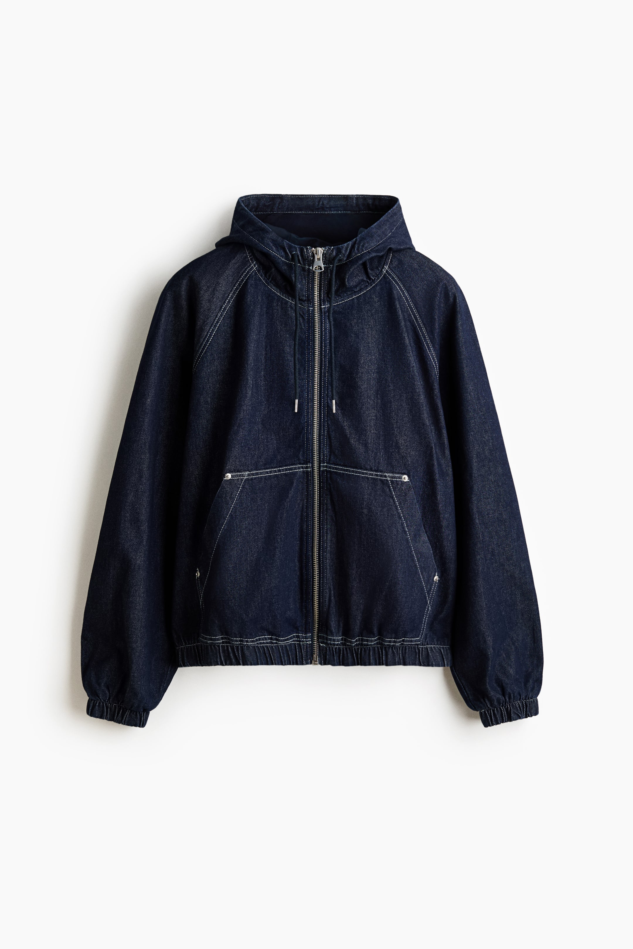 View larger image: A dark blue denim hooded jacket is shown from the front, featuring a full silver-tone zip closure and white contrast stitching throughout. It is designed with raglan sleeves, two large front patch pockets, and elasticated cuffs and hem.