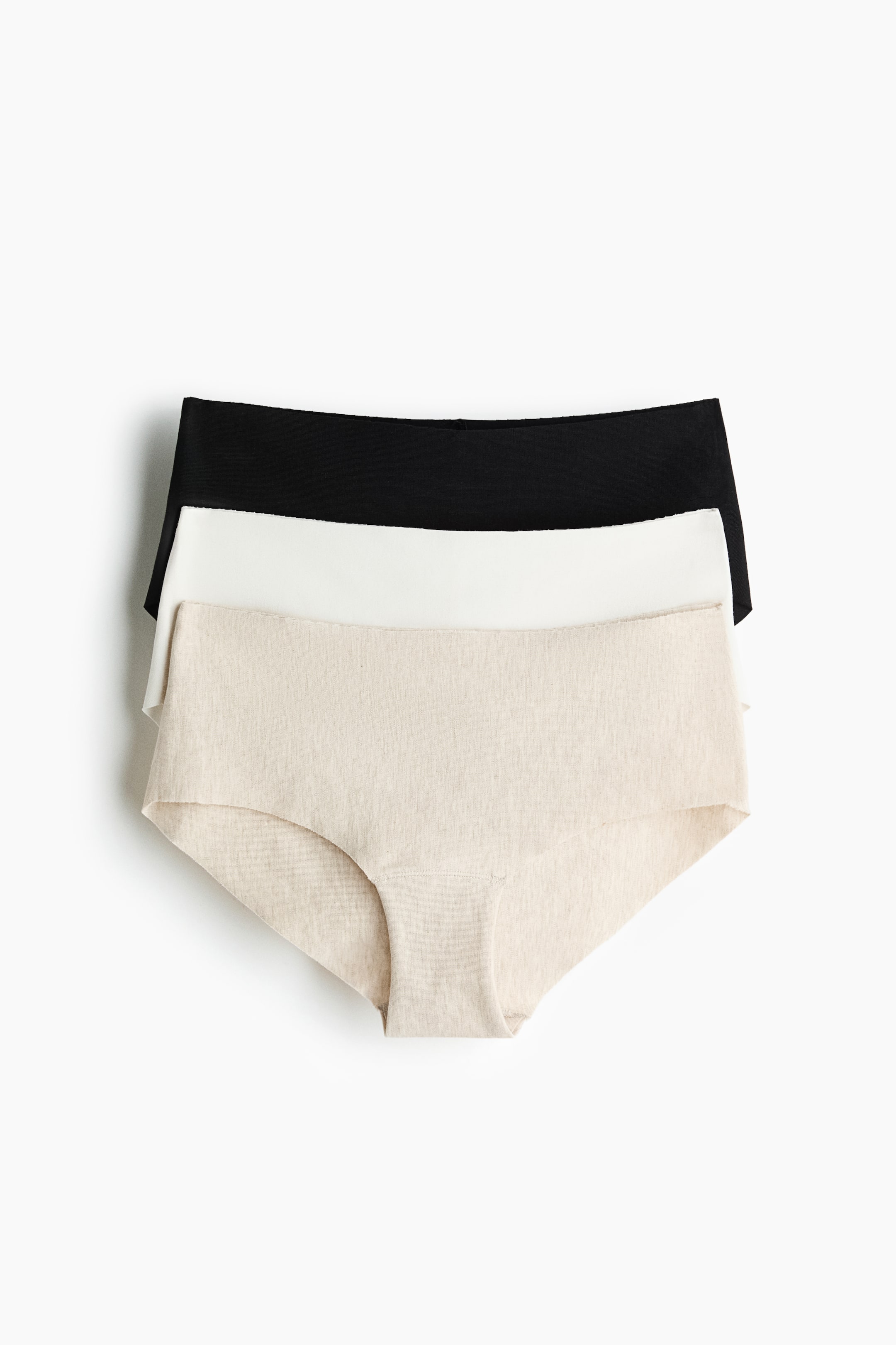 הצגת תמונה גדולה יותר: שלושה זוגות תחתונים ללא תפר מוצגים מונחים זה על גבי זה בהצגה מהחזית: הזוג העליון שחור, האמצעי לבן והתחתון בז' בהיר במרקם מלנג'. כל זוג בעל גזרה נמוכה עם שוליים חלקים, ללא קיפולים או תפרים.