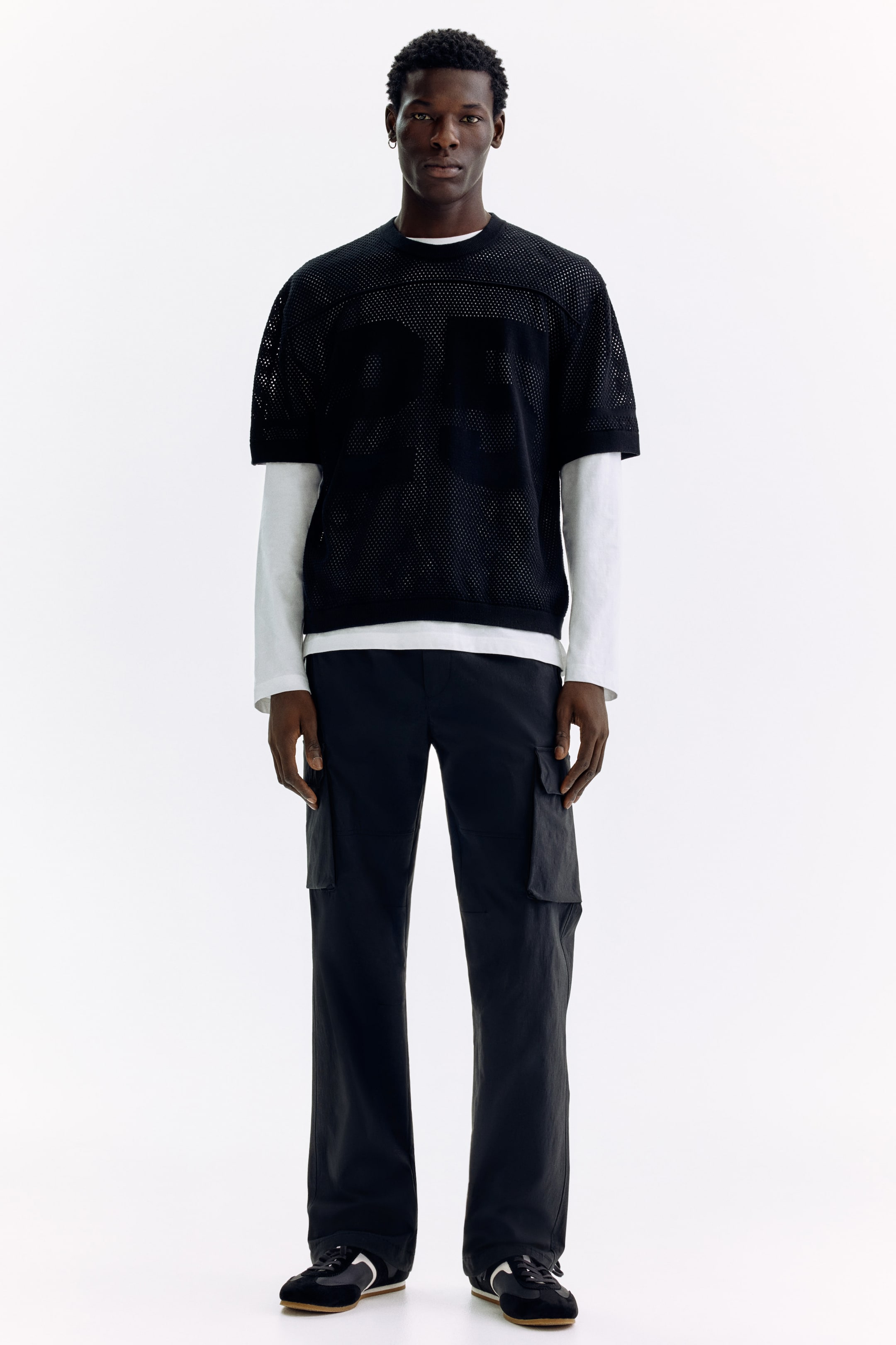 Voir une image plus grande: Un haut de style maillot en maille noire avec un col rond, des manches courtes et un panneau supérieur uni au niveau de la poitrine. De grands chiffres "05" sont visibles sur le devant, et il est superposé à une chemise blanche à manches longues.