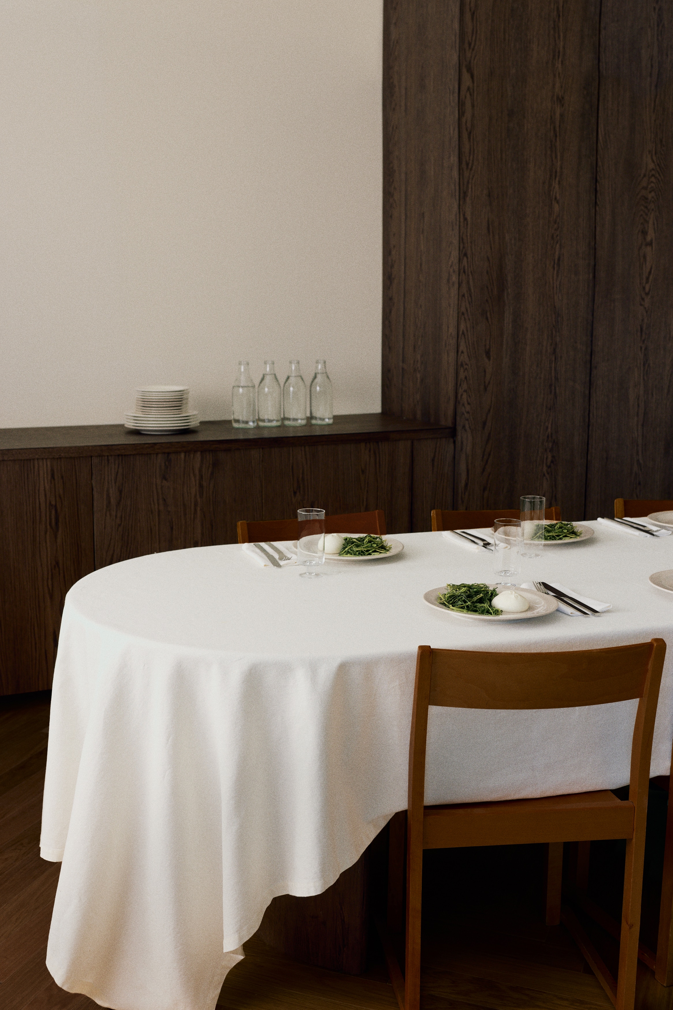 Two round, light beige plates are positioned vertically, one above the other. Each plate is displaying a flat center and a slightly raised outer rim.