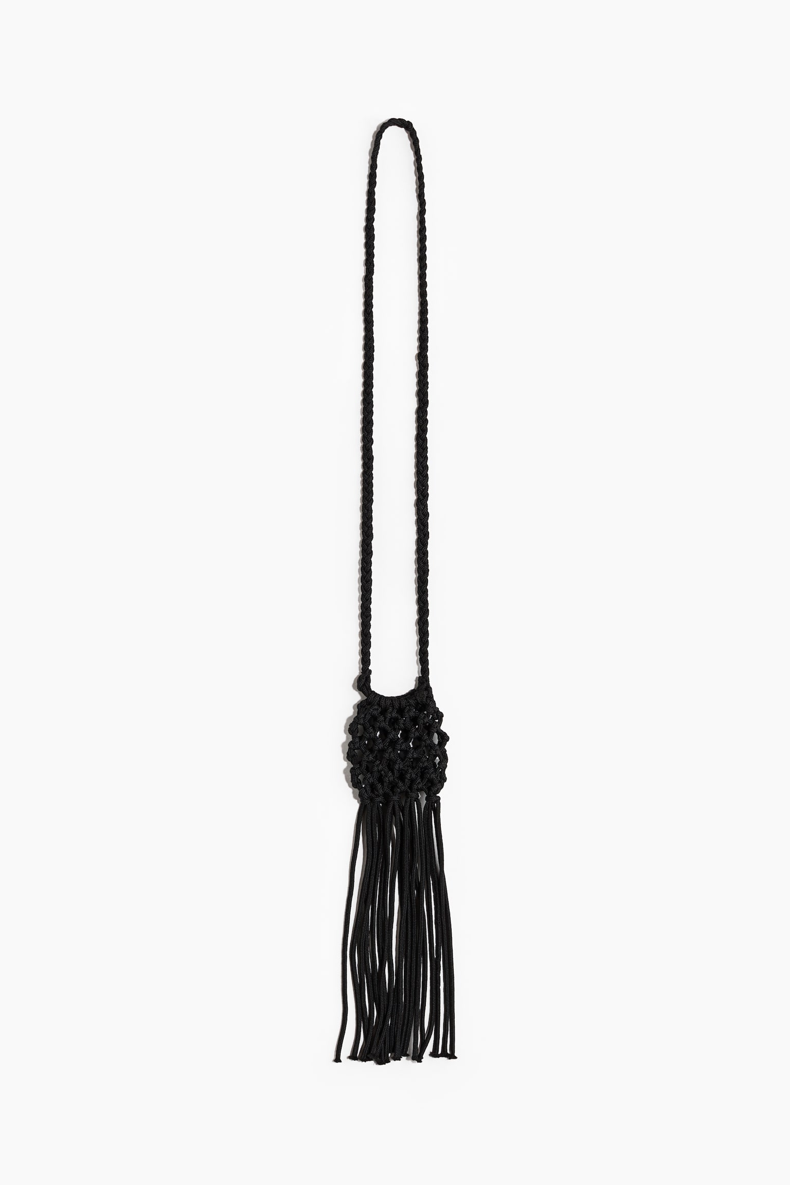 Un accesoriu macrame negru prezintă o curea lungă împletită care formează o buclă în partea de sus, ducând la o secțiune rotundă de macrame cu noduri complexe, din care atârnă mai multe fire de cordon, creând un ciucure. - 1