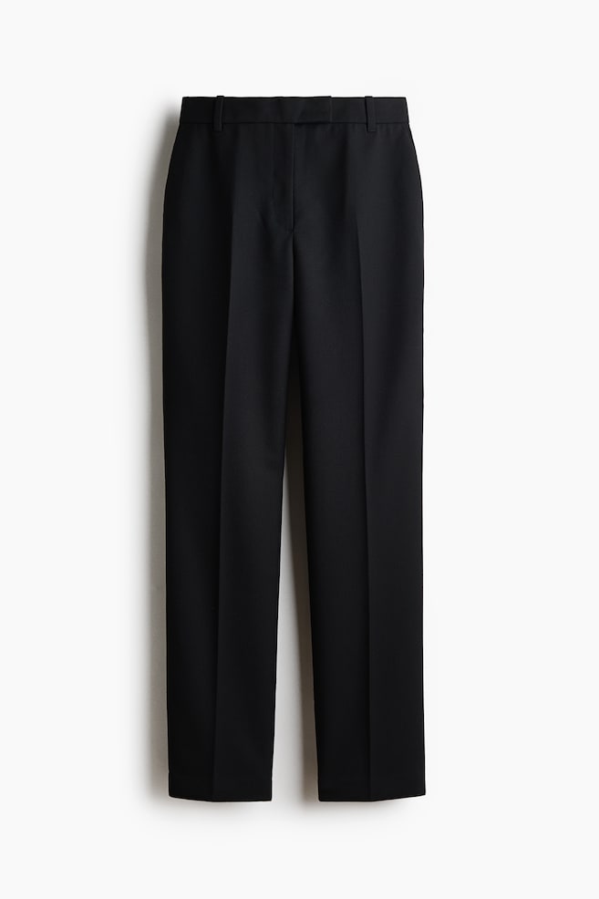 Une paire de pantalons noirs à coupe slim est présentée de face, avec des plis marqués et nets courant verticalement au centre de chaque jambe. Le pantalon est doté dâune taille épurée avec passants pour ceinture et dâune fermeture frontale dissimulée, mettant en valeur sa structure tailleur. - 1