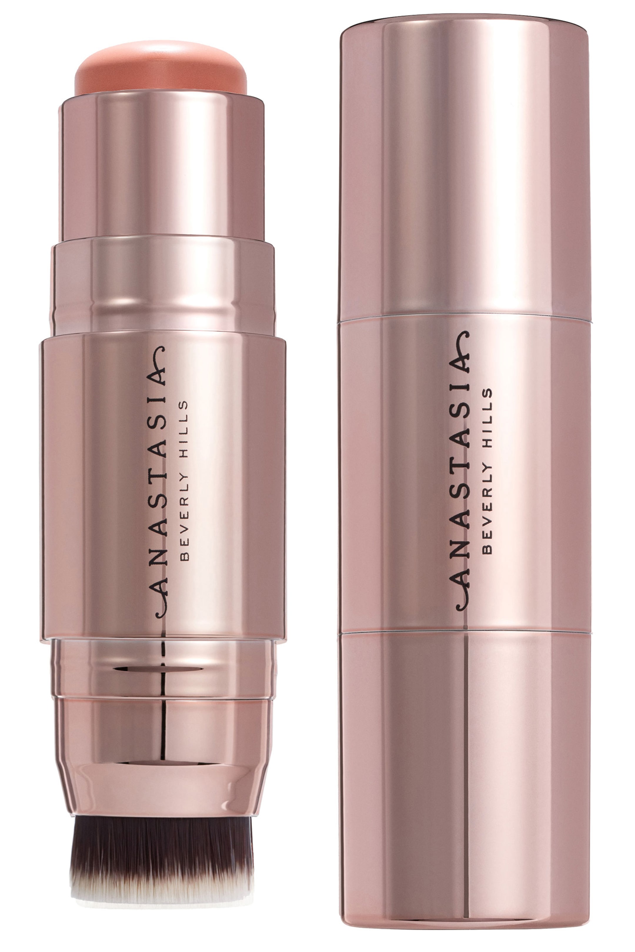 Näytä suurempi kuva: Kaksi metallista ruusukullanväristä meikkipuikkoa seisovat pystyasennossa, ja kummassakin on "ANASTASIA BEVERLY HILLS" painettuna pystysuunnassa niiden sivuille. Yksi puikko näyttää pyöreän persikka-pinkin tuotteen yläosassaan ja tummista ja vaaleista harjaksista koostuvan harjasapplikaattorin alaosassaan, kun taas toinen puikko on täysin suljettu.