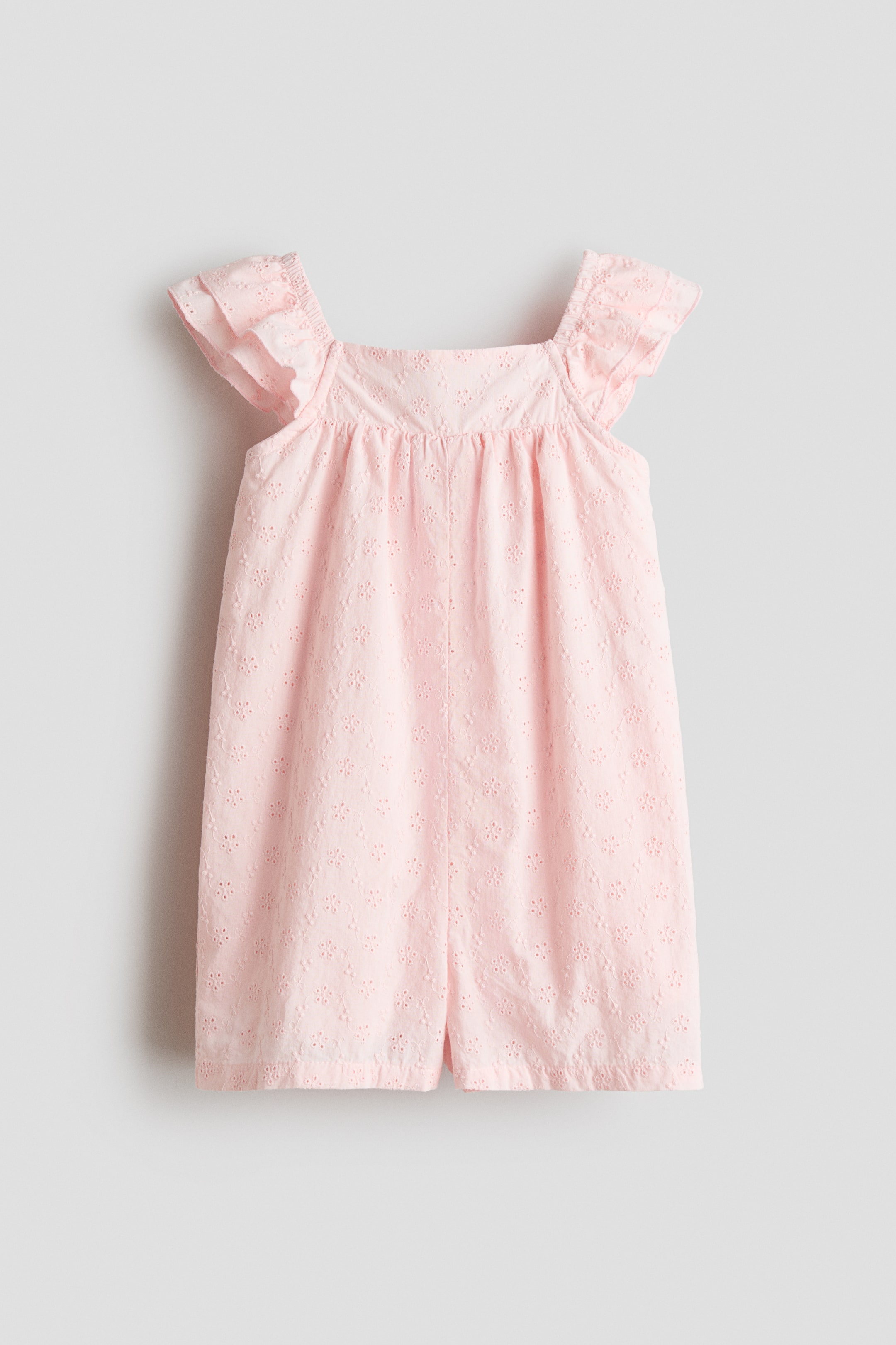 Ver imagen más grande: Un mono rosa presenta su vista frontal, con un escote cuadrado y mangas dobles con volantes. La prenda está confeccionada en un tejido ligero con bordado de ojales en toda su superficie.