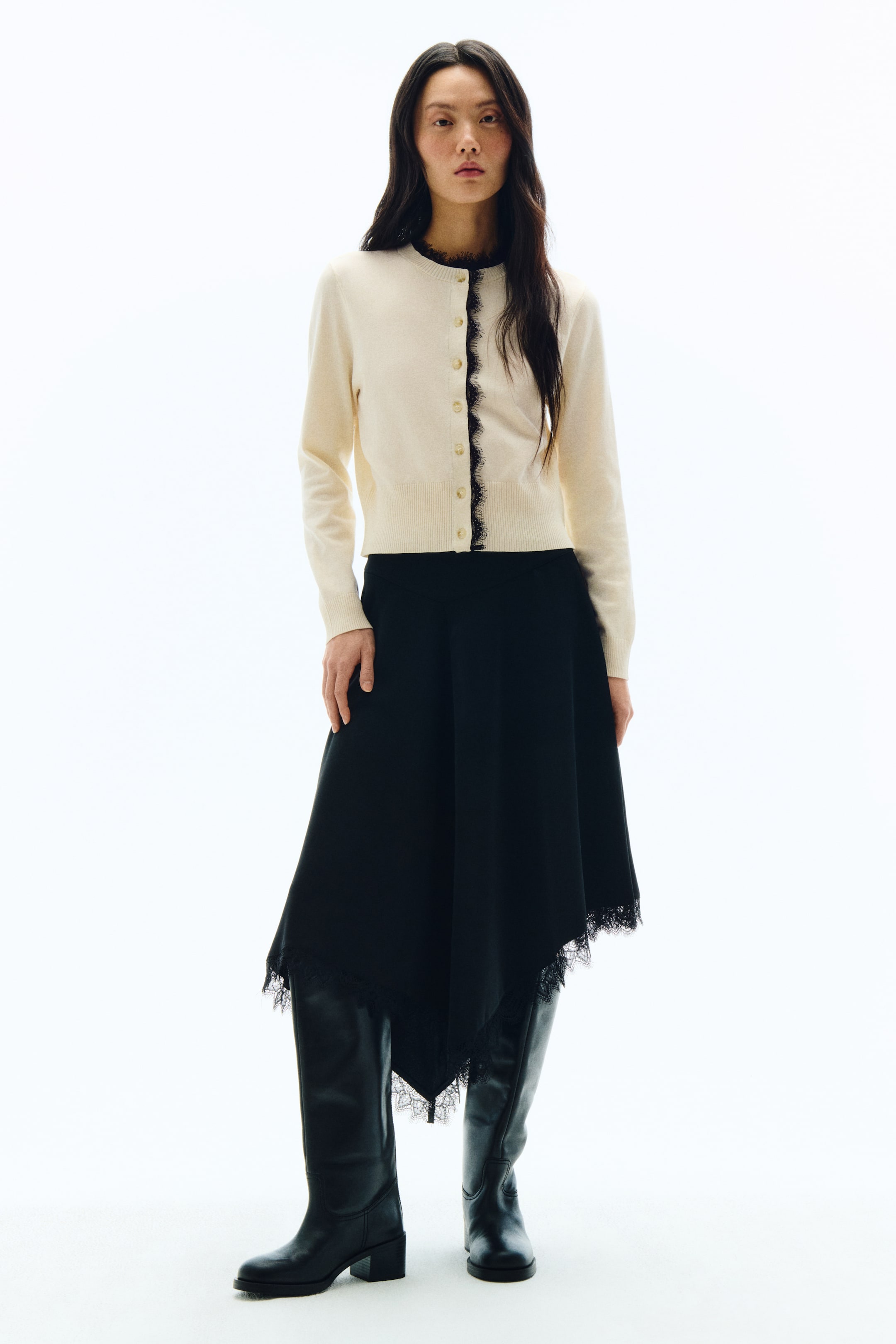 이미지 확대 보기: 블랙 미디 스커트로, 유려하게 떨어지는 비대칭 헴라인에 블랙 레이스 트리밍 디테일이 더해진 디자인입니다.