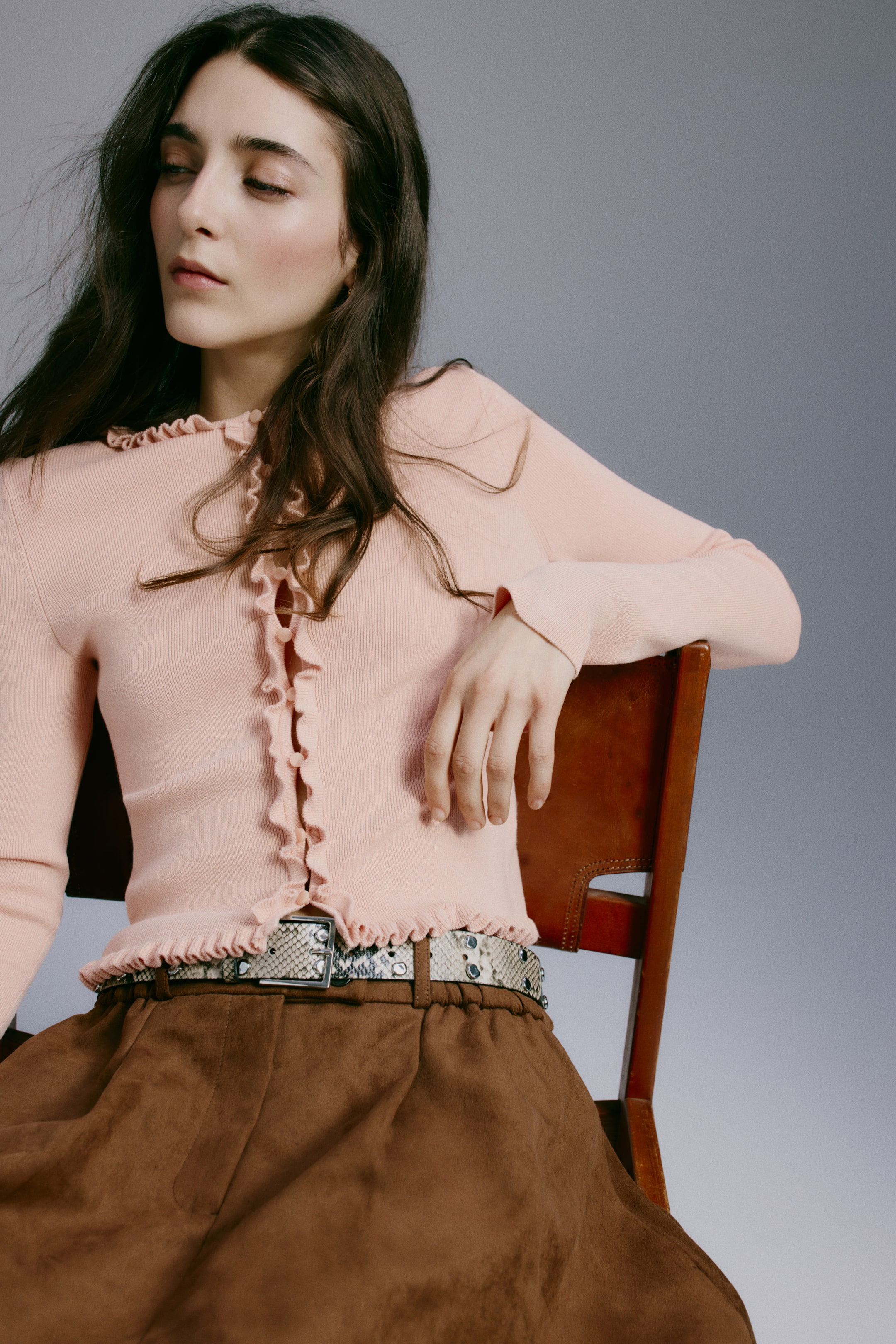 Ver imagen más grande: El cárdigan acanalado rosa presenta una tapeta con botones adornada con volantes, un escote con volantes y un ribete con volantes a lo largo del dobladillo y los puños de las mangas. Se lleva ajustado, revelando parcialmente un cinturón con estampado de piel de serpiente debajo del dobladillo.