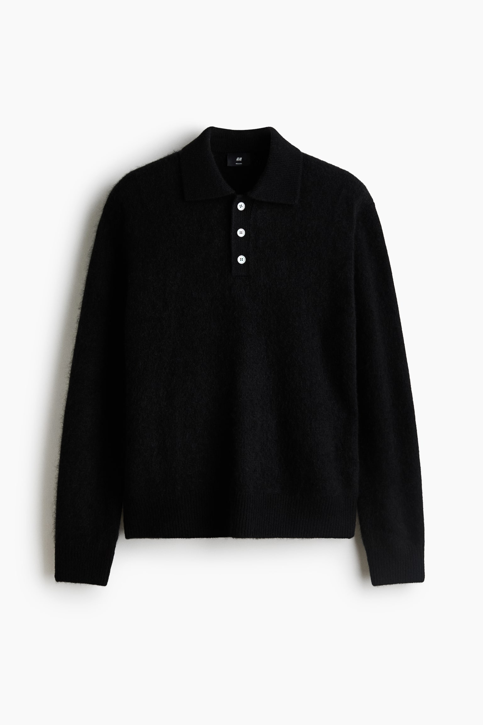 Un polo noir Ã  manches longues en tricot de laine doux et duveteux, prÃ©sentÃ© de face, mettant en valeur un col classique, une patte de boutonnage Ã  trois boutons avec des boutons blancs contrastants, ainsi quâun fini cÃ´telÃ© aux poignets et Ã  lâourlet.