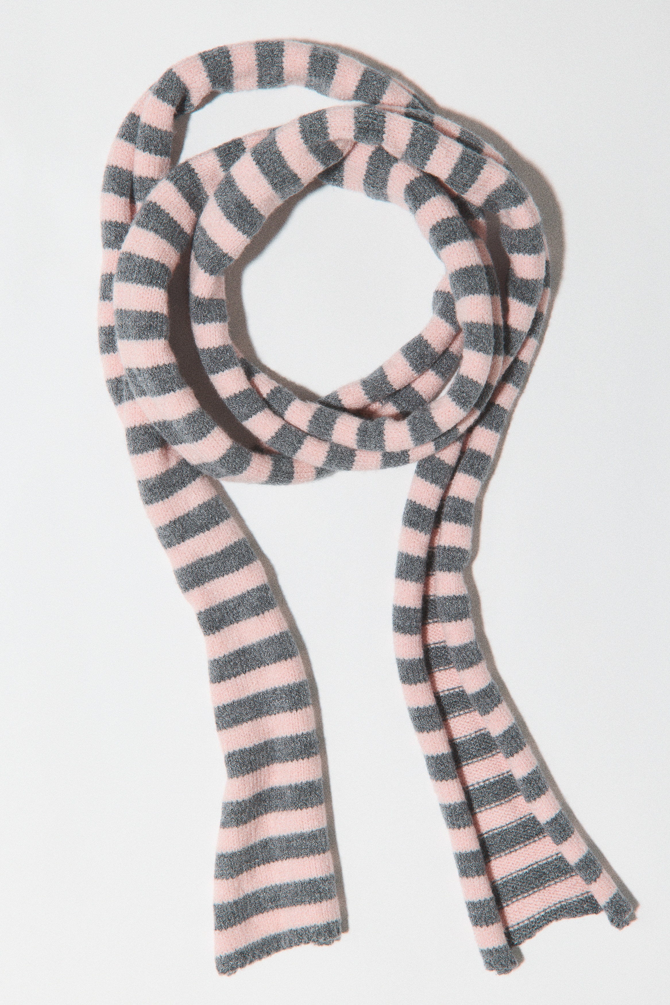 A long, narrow scarf in a viscose-blend knit is shown with alternating horizontal stripes of light pink and gray. The scarf is arranged in a loop at the top, with two long ends hanging down.