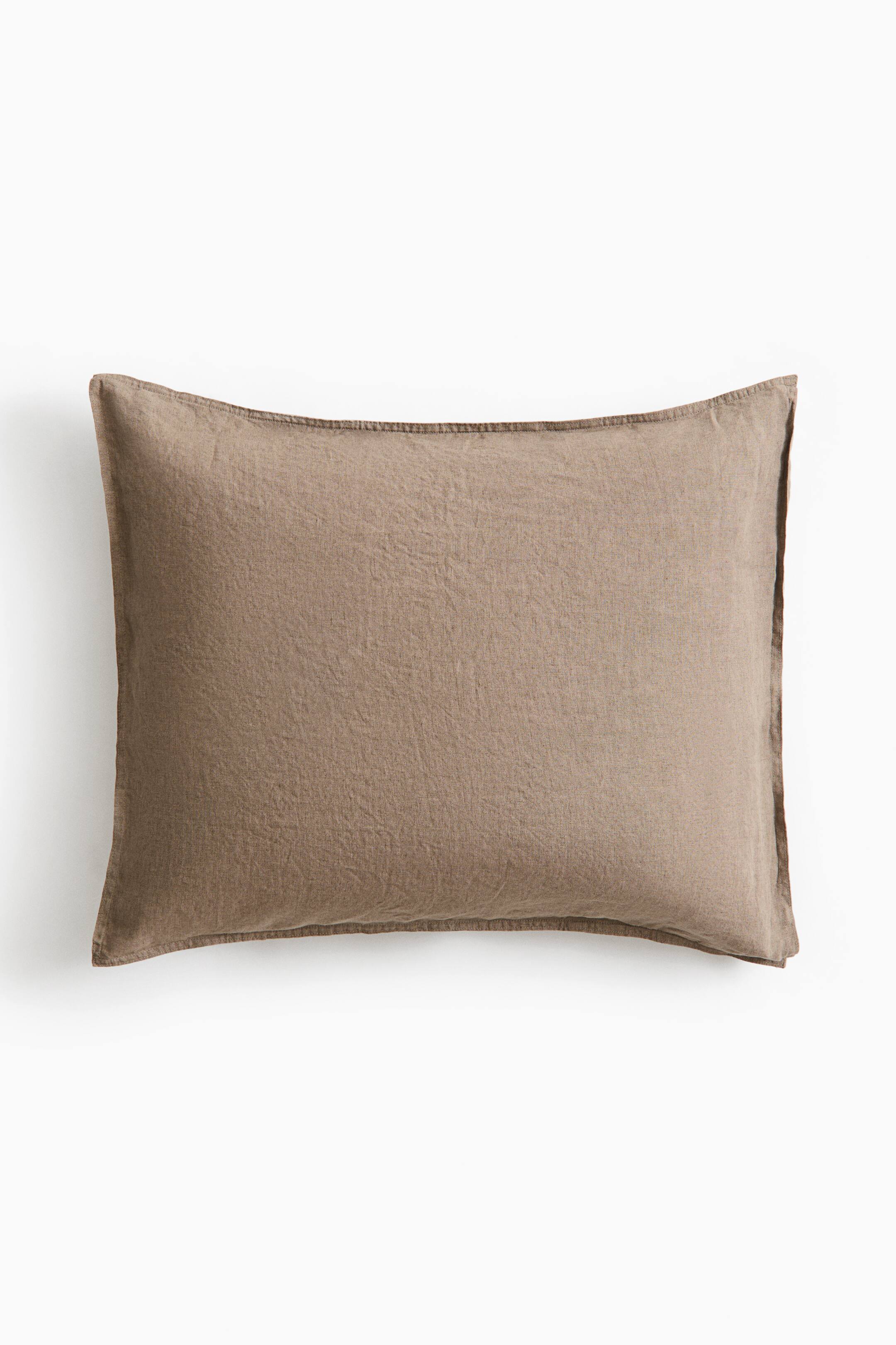 View larger image: A rectangular washed linen pillowcase in a light brown shade is shown from the front, highlighting its textured, slightly wrinkled finish. The pillowcase features double-stitched flange edges along all four sides.