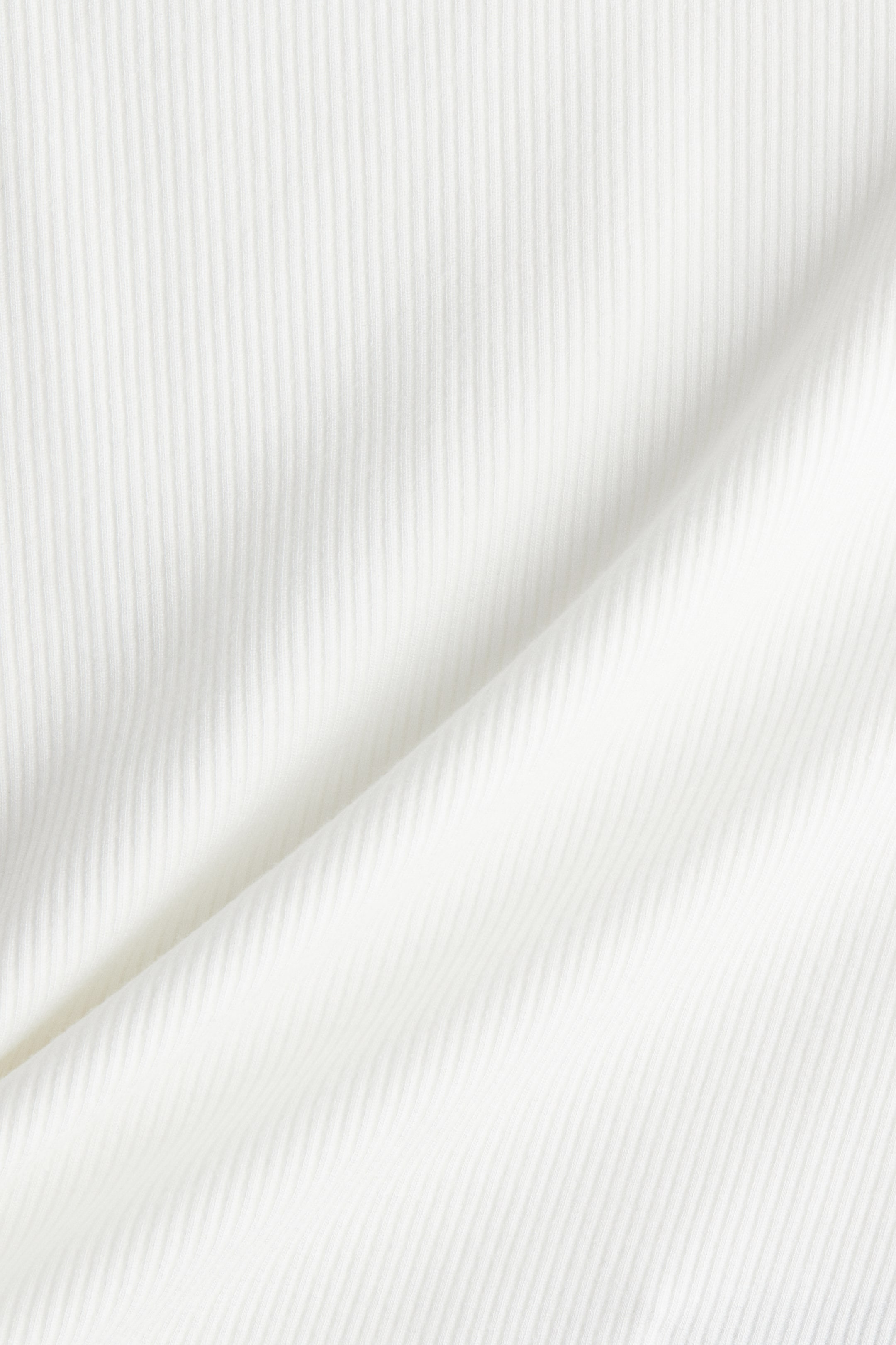 View larger image: A white ribbed fabric is showcasing a textured pattern with noticeable vertical lines and gentle drapes.