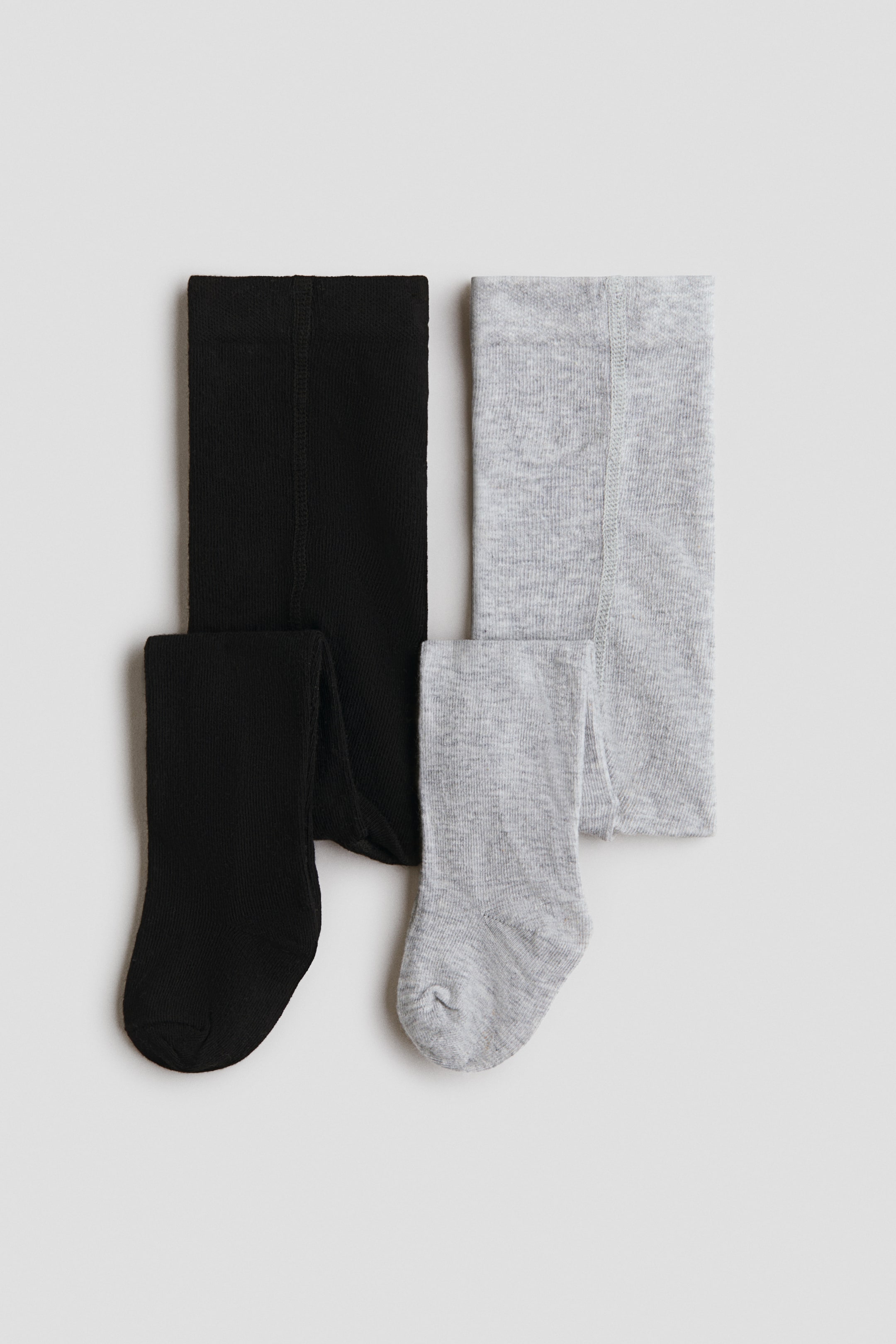 View larger image: Two pairs of tights, one black and one heather gray, are laid flat, each featuring a fine knit texture, a visible vertical seam, and visible foot sections at the bottom.