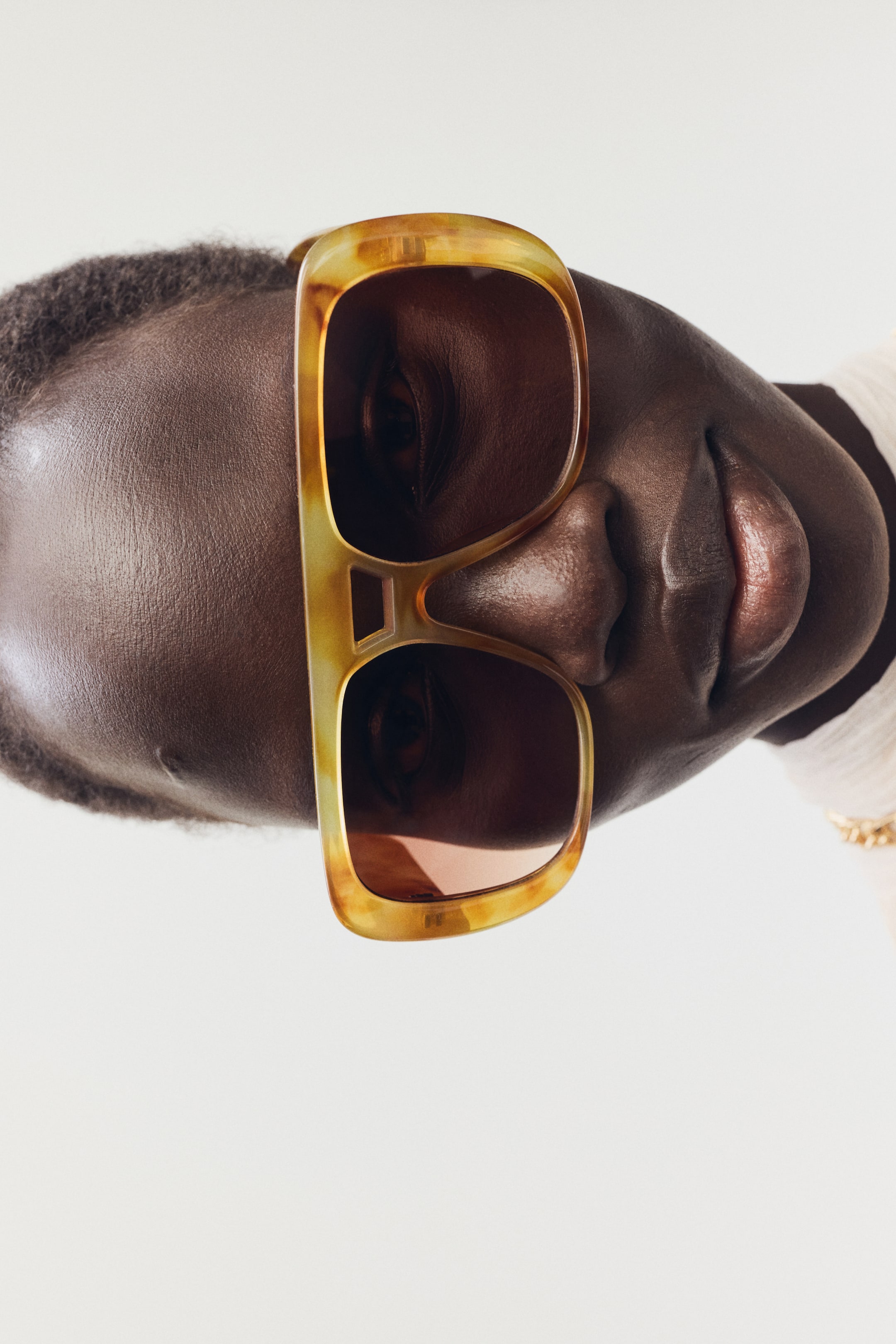 Größeres Bild anzeigen: Breite, rechteckige Sonnenbrillen im Schildpatt-Look mit dunkel getönten Gläsern und einem markanten Ausschnitt-Design an der Brücke. Sie werden auf einem Gesicht getragen.