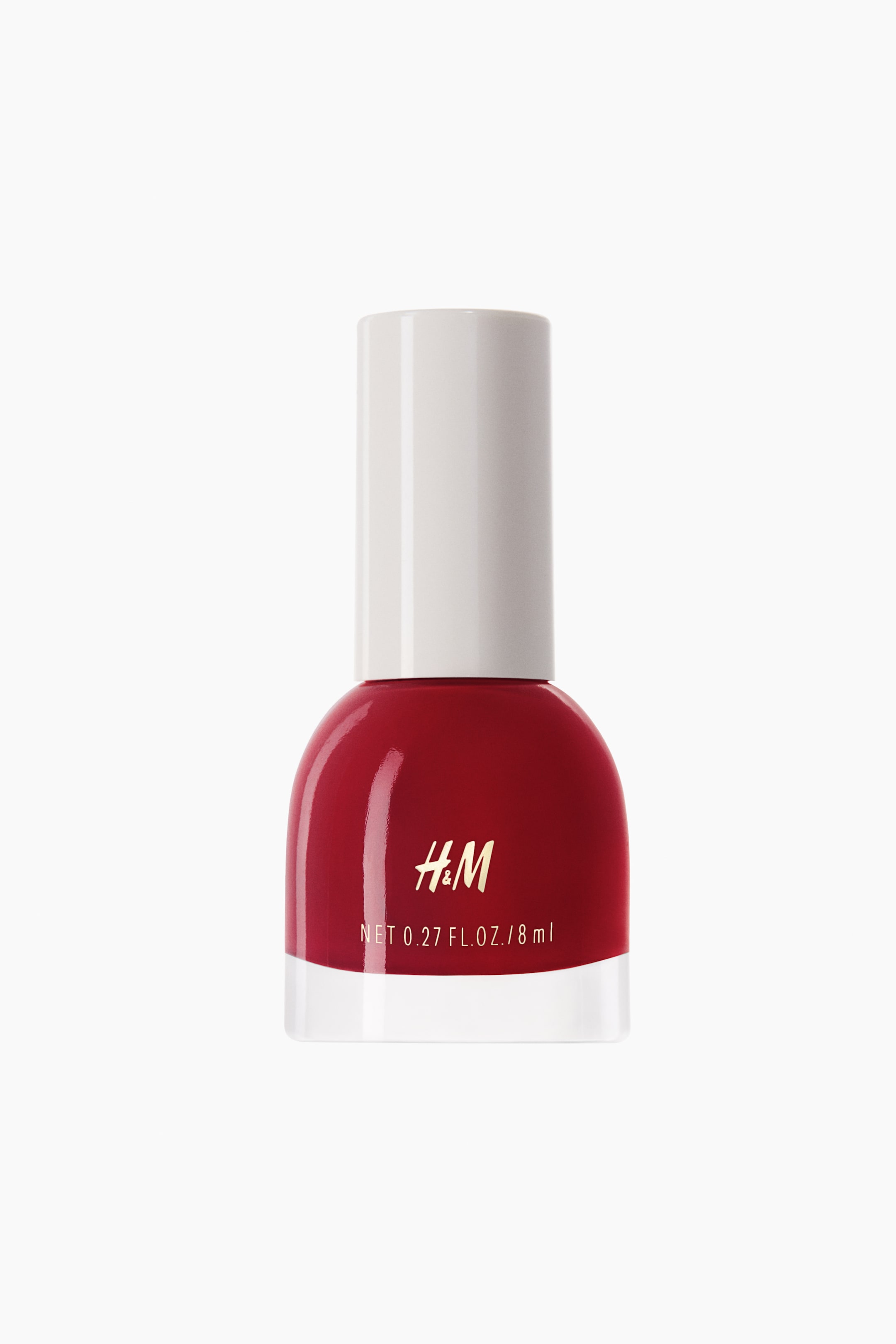 View larger image: Nail polish is shown from the front, featuring a rounded glass bottle filled with glossy, deep red polish and topped with a cylindrical white cap. The front of the bottle displays a gold "H&M" logo above the printed text "NET 0.27 FL.OZ. / 8 ml".