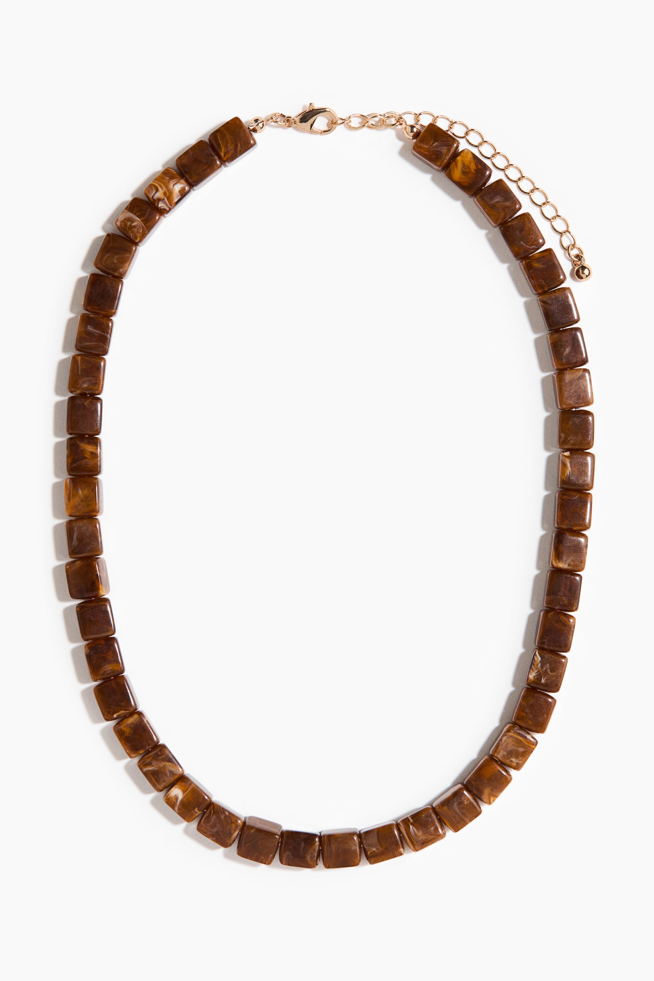 Se større billede: Et halskæde danner en oval form, med firkantede, marmorerede brune perler, en guldfarvet hummerklo-lås og en forlængerkæde.