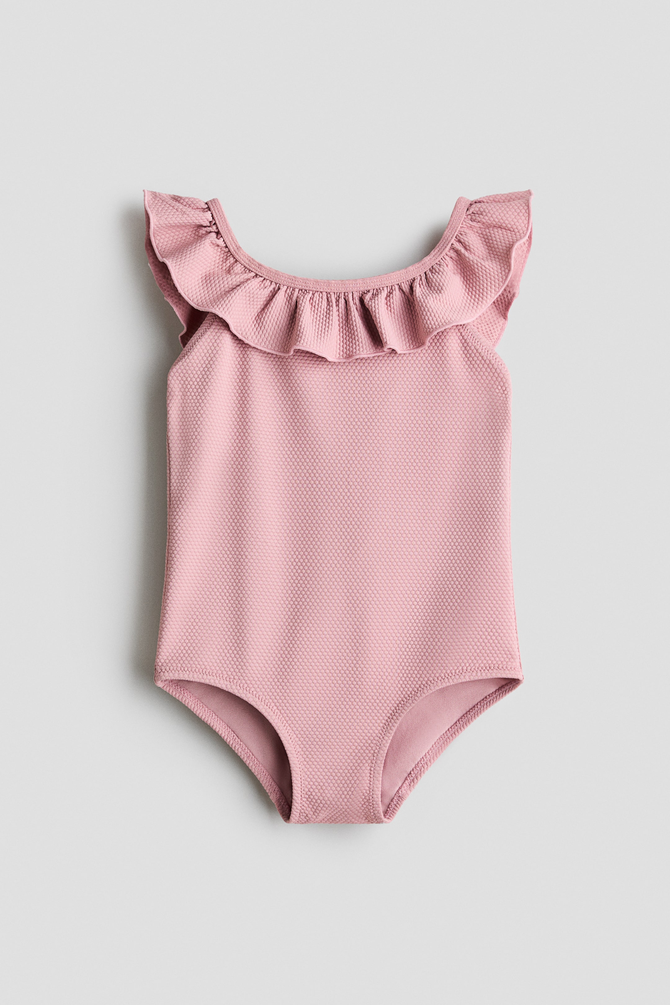 Ingrandisci l'immagine: Un costume da bagno intero in maglia rosa con texture è esposto dalla parte anteriore. Presenta uno scollo arricciato e maniche a cappuccio arricciate.
