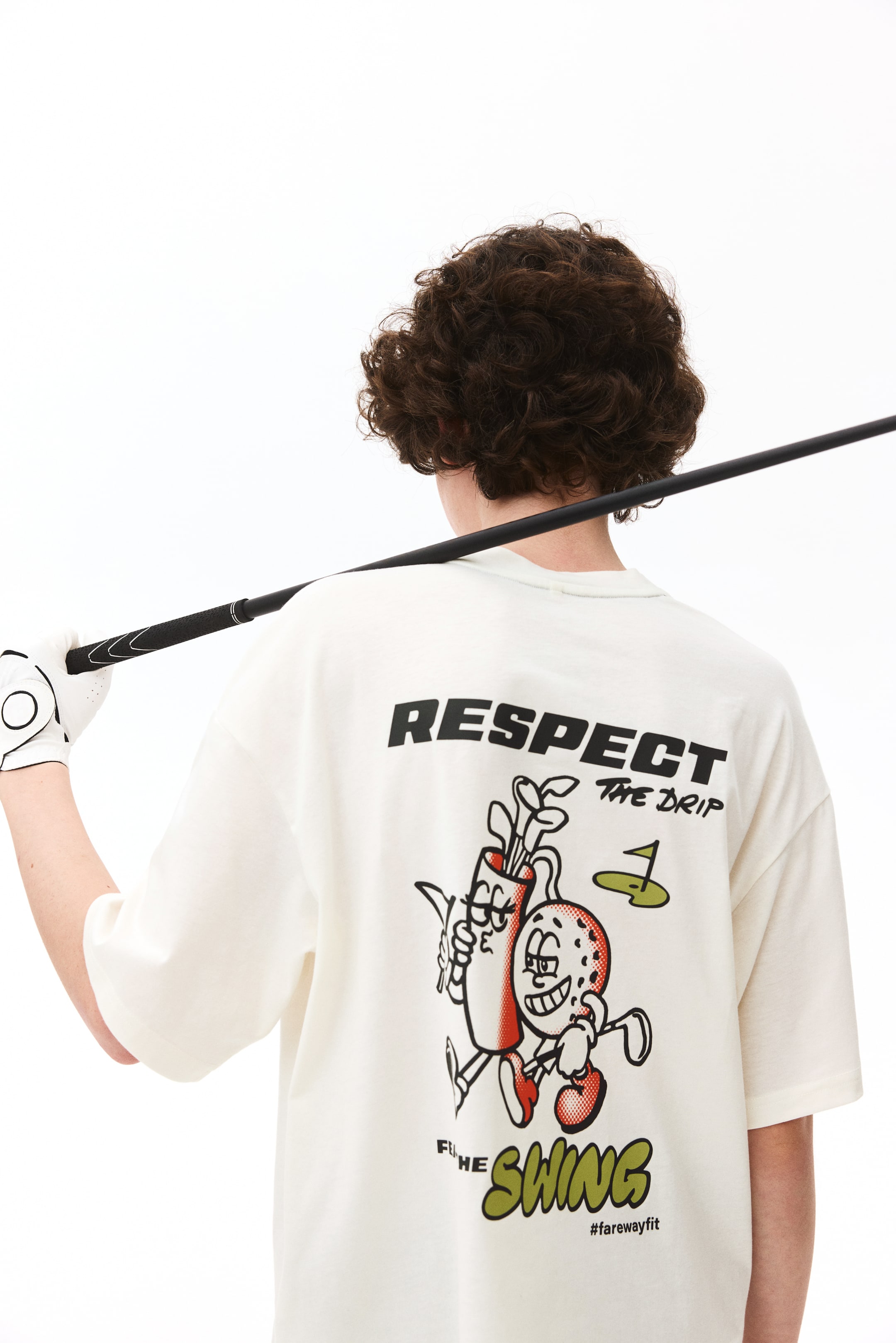 View larger image: An off-white t-shirt is displayed from the back, highlighting a crew neck and short sleeves. The rear showcases black "RESPECT THE DRIP" text above a cartoon graphic depicting a golf bag with clubs and a golf ball character holding a club. Below, green "THE SWING" text and "#farewayfit" are printed.