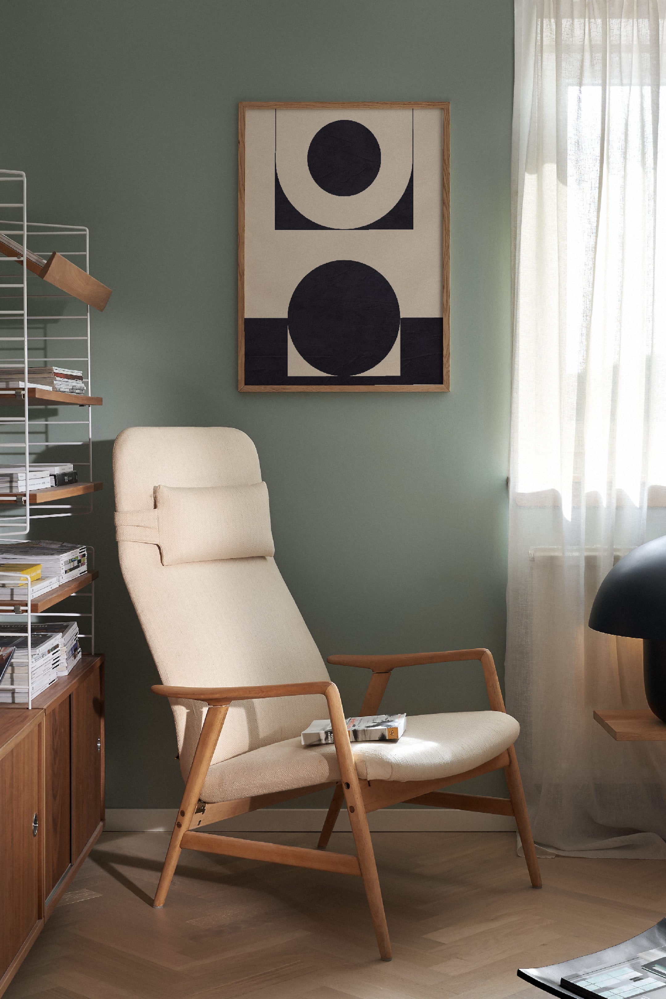 View larger image: An armchair is showcasing a light wooden frame and cream fabric upholstery, angled slightly to the right. A separate headrest pillow, also in cream fabric, is attached to the back with straps, and a book is resting on its seat.