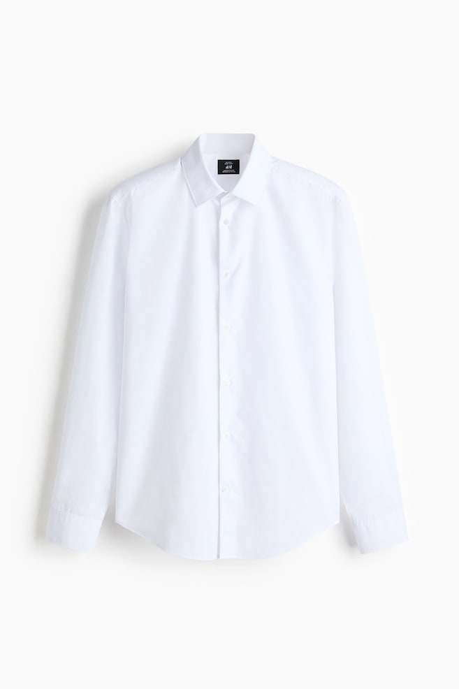 A white, long-sleeved dress shirt is shown facing the front, showcasing a structured turn-down collar and a classic button-up front. The shirt is featuring a slim-fit silhouette with a gently rounded hem and buttoned cuffs. - 1