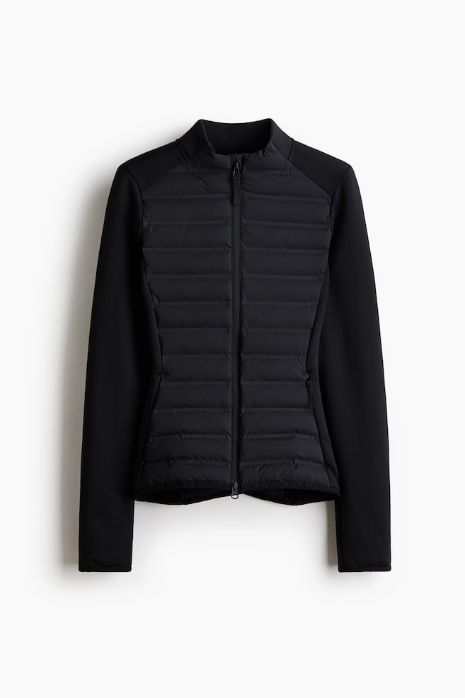A black hybrid padded jacket is showcased from the front, featuring a horizontally quilted front body, smooth sleeves, a stand-up collar, a full-length front zipper, and two zippered side pockets. - 1