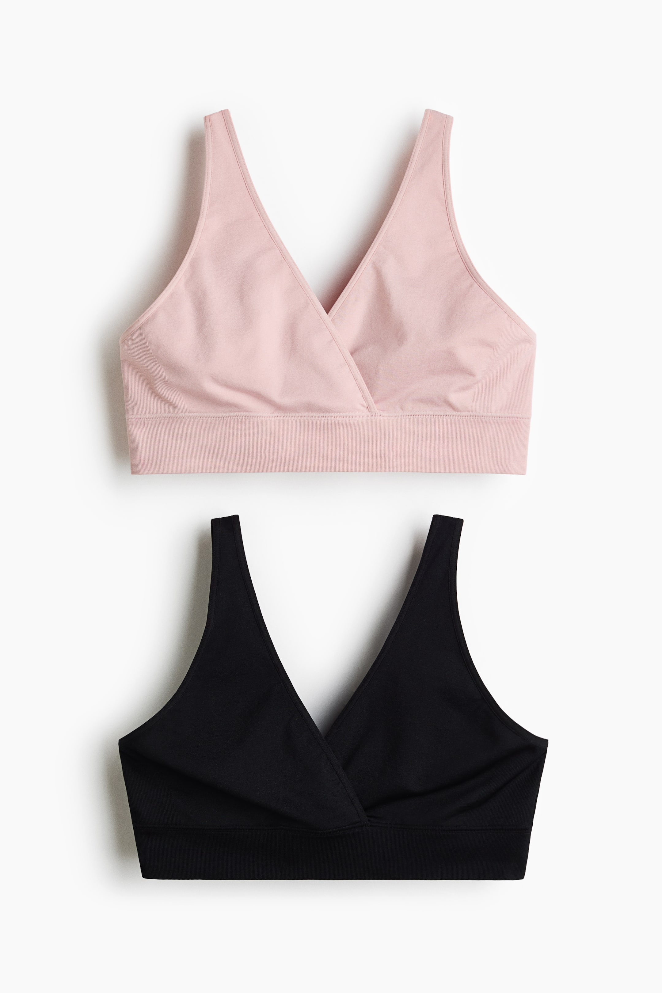 Agrandir l'image: Deux soutiens-gorge d'allaitement doux, l'un rose clair et l'autre noir, sont présentés face avant. Chaque soutien-gorge est doté de larges bretelles, d'un devant croisé et d'une large bande côtelée à l'ourlet, apparaissant sans couture et sans attaches visibles.