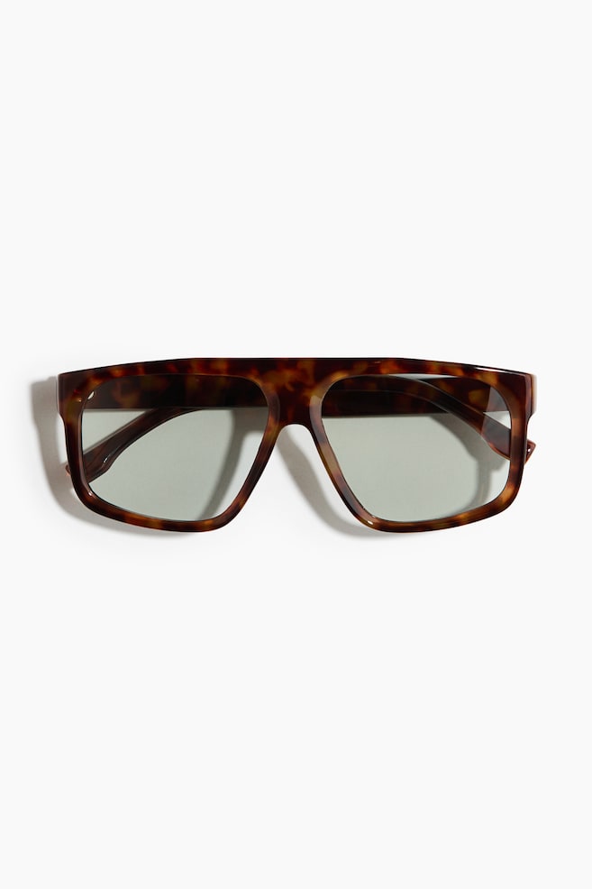 Sunglasses boast a broad, rectangular tortoiseshell frame paired with light grey-green lenses, offering a flat, forward-facing design. - 1