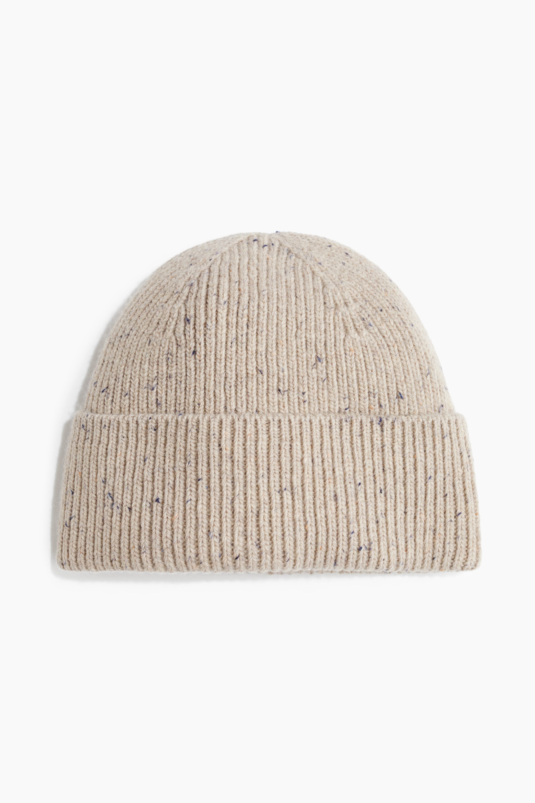 Voir une image plus grande: Un bonnet tricoté côtelé beige est présenté de face. Il présente un revers replié, et son tricot est parsemé de petites taches foncées.