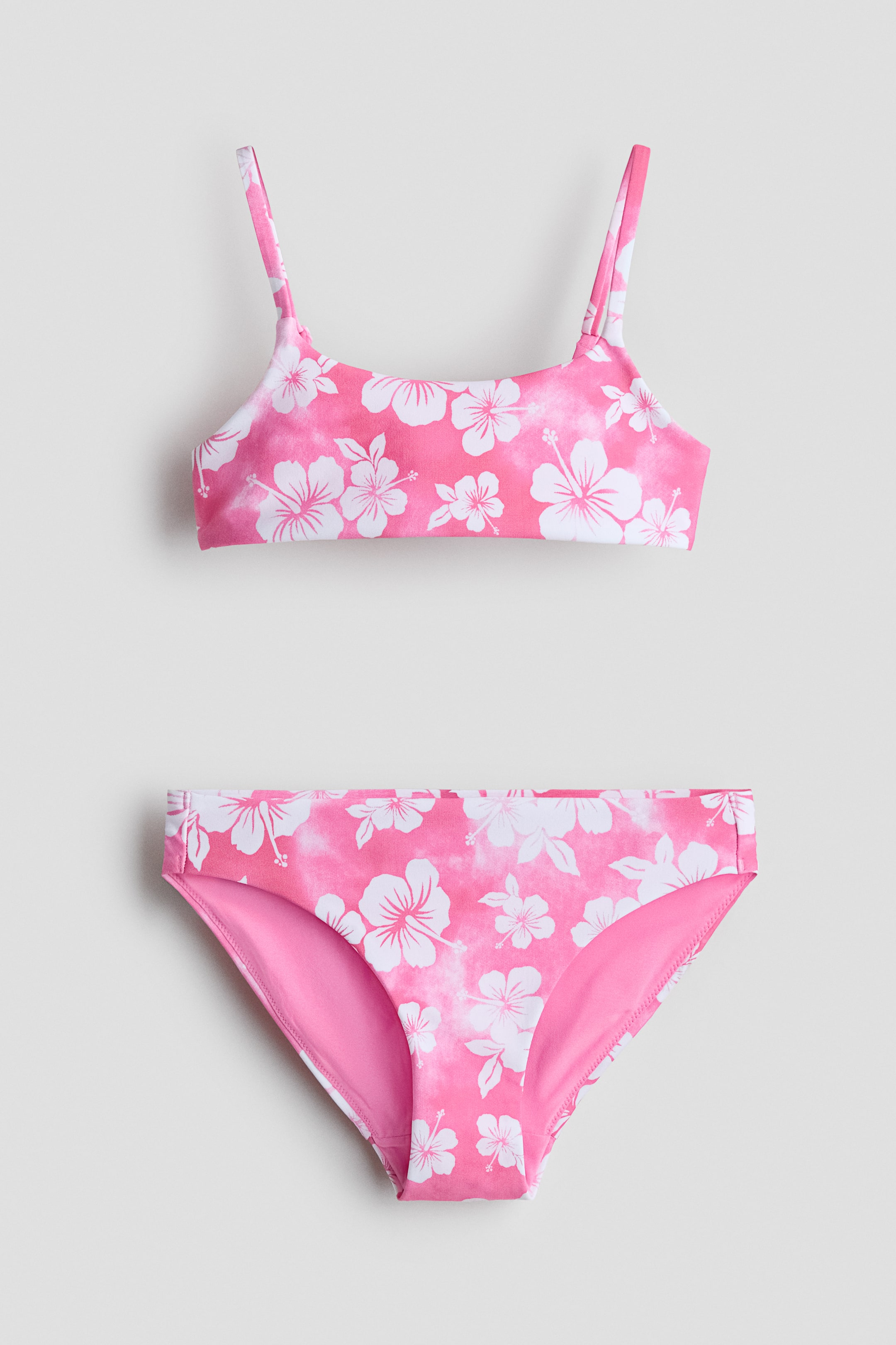 Ver imagen más grande: Conjunto de bikini completamente forrado, compuesto por un top con tirantes estrechos y ajustables, y braguitas a juego. Ambas piezas lucen un estampado floral de hibisco en rosa y blanco con un efecto tie-dye.