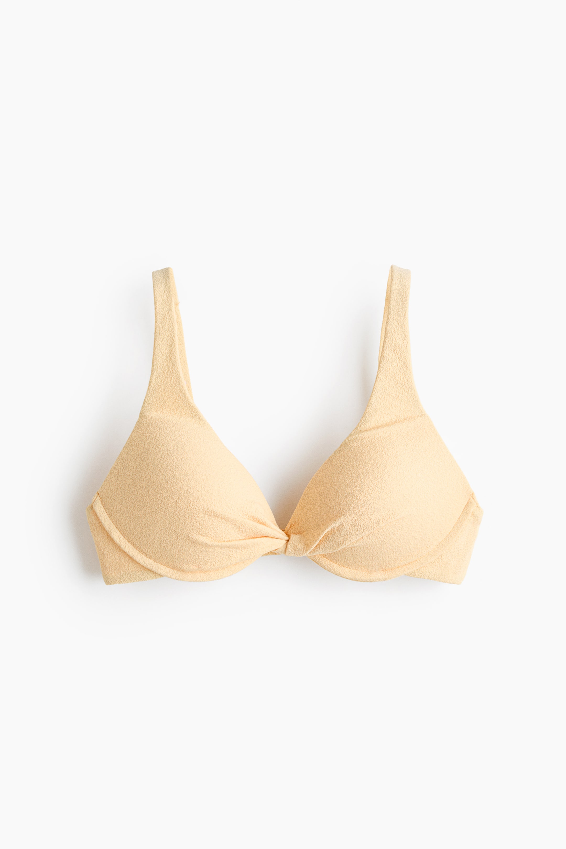 Grotere afbeelding bekijken: Een lichtbeige bikinitop wordt van voren getoond, met gestructureerde, gewatteerde cups en een gedraaid detail in het midden van de buste, samen met schouderbandjes en een subtiel getextureerde stof.